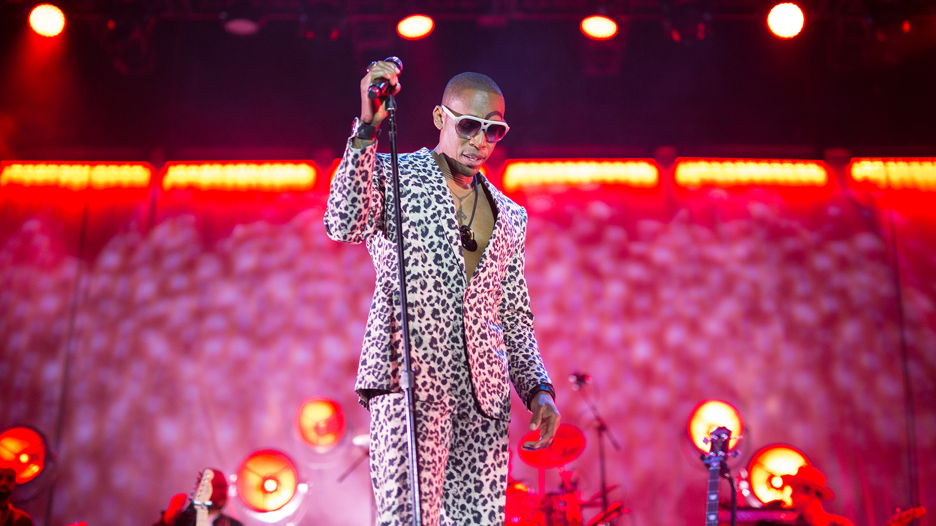 Black man on stage with mic in animal print suit