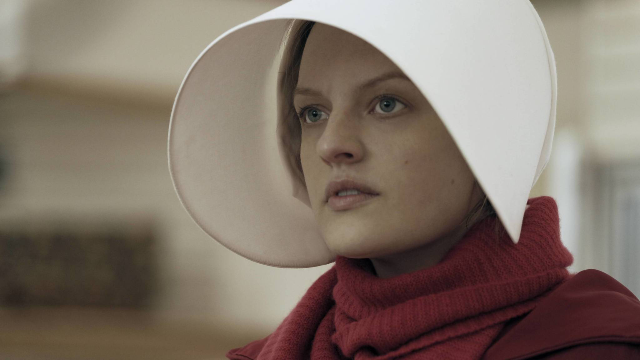 A white woman wearing a white bonnet with a rim that frames her face exaggeratedly stands in side profile. She is wearing a red robe that stretched up to her chin.