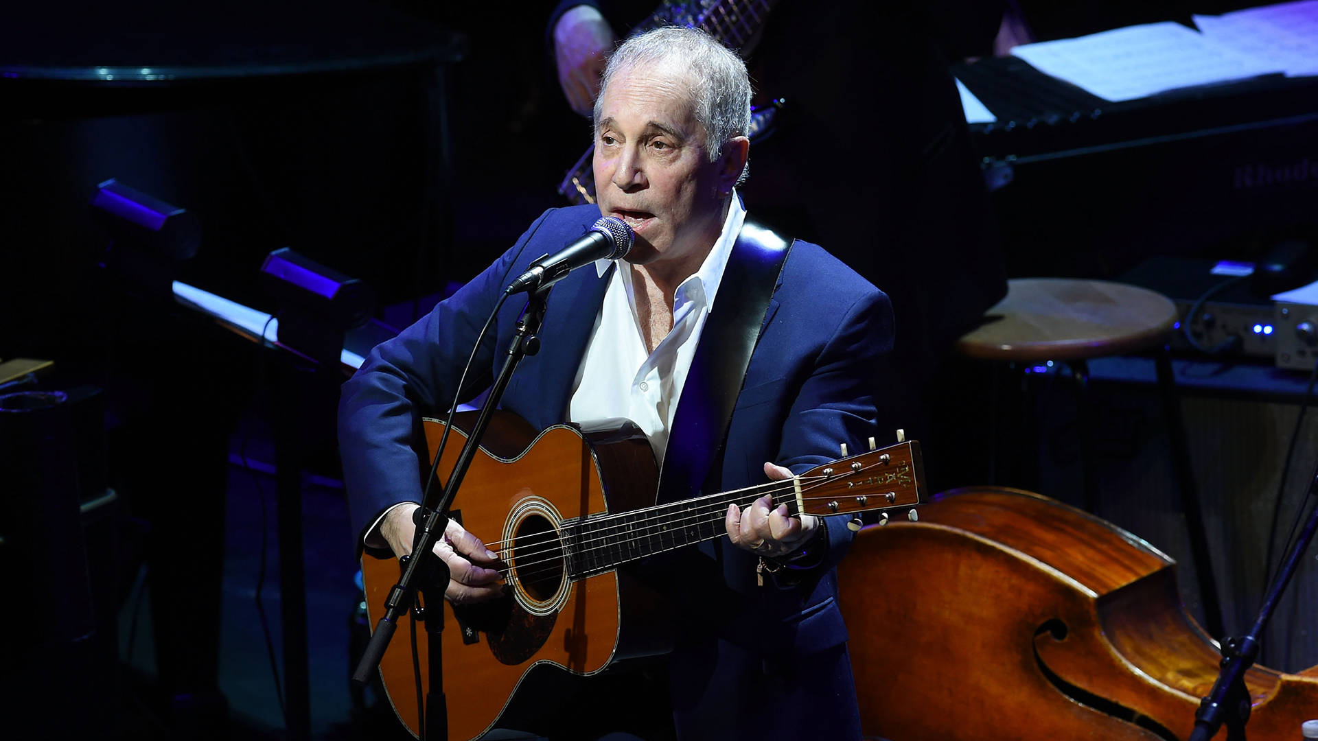 older white man with guitar singing into mic with guitar