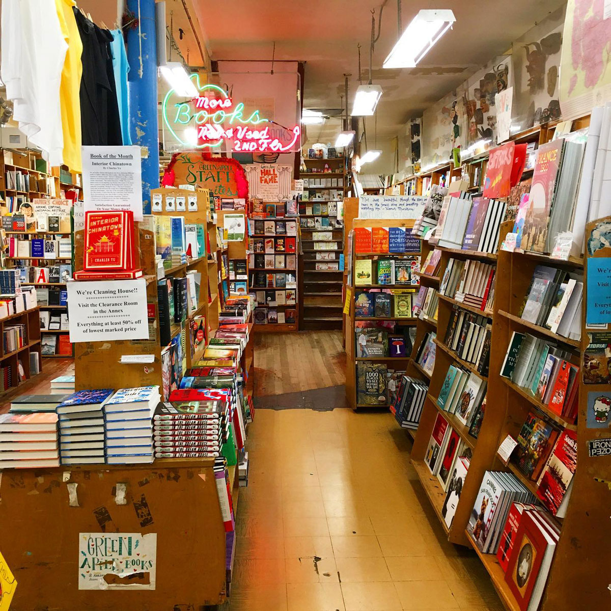 The interior of a bookstore with packed shelves against the walls and display tables in between.