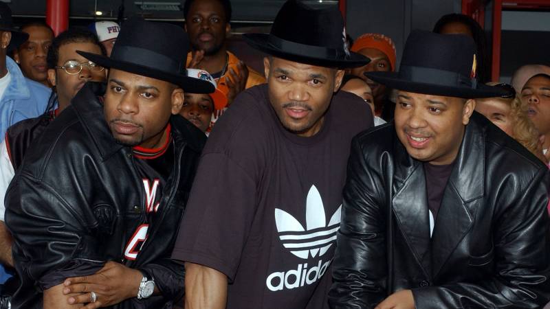 Three Black men wearing black clothes and hats stand together in a line.