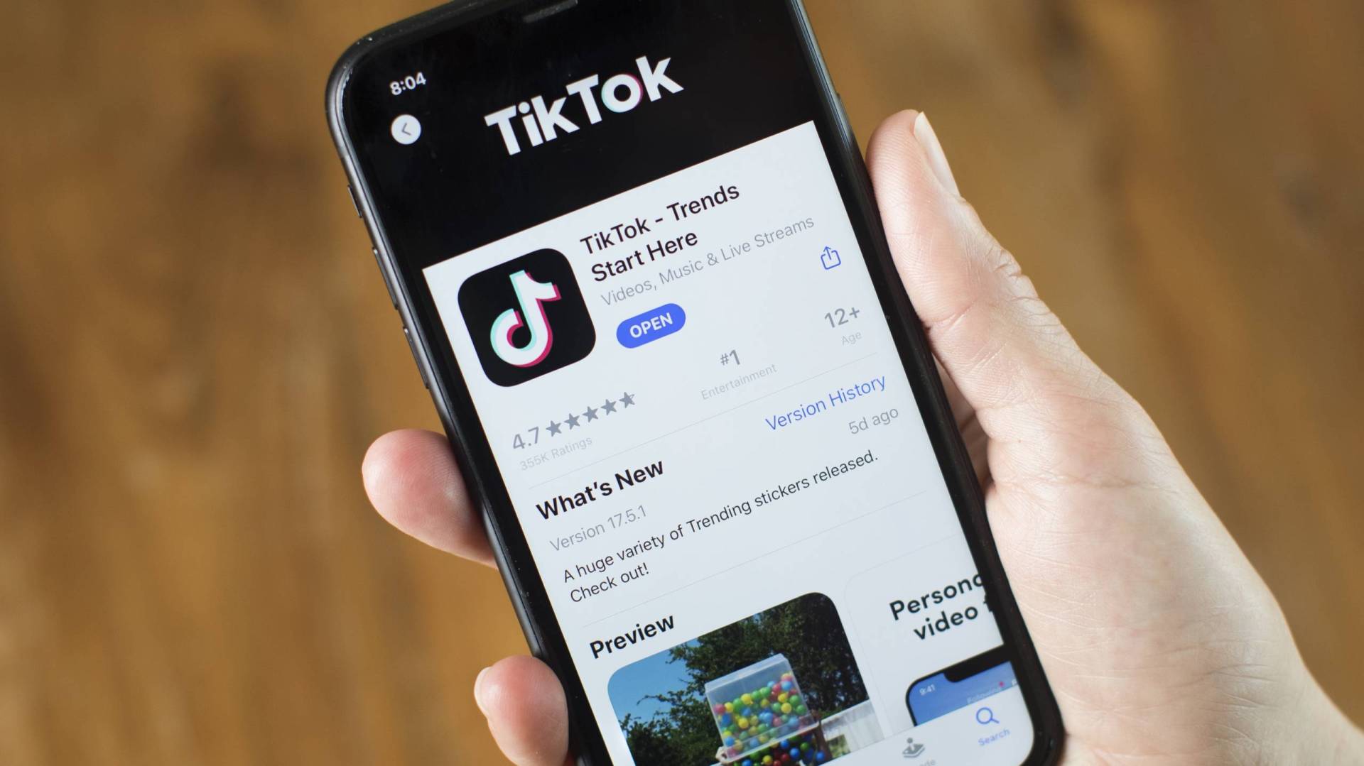 The download page for ByteDance Ltd.'s TikTok app is visible on a cell phone being held in the palm of a hand.