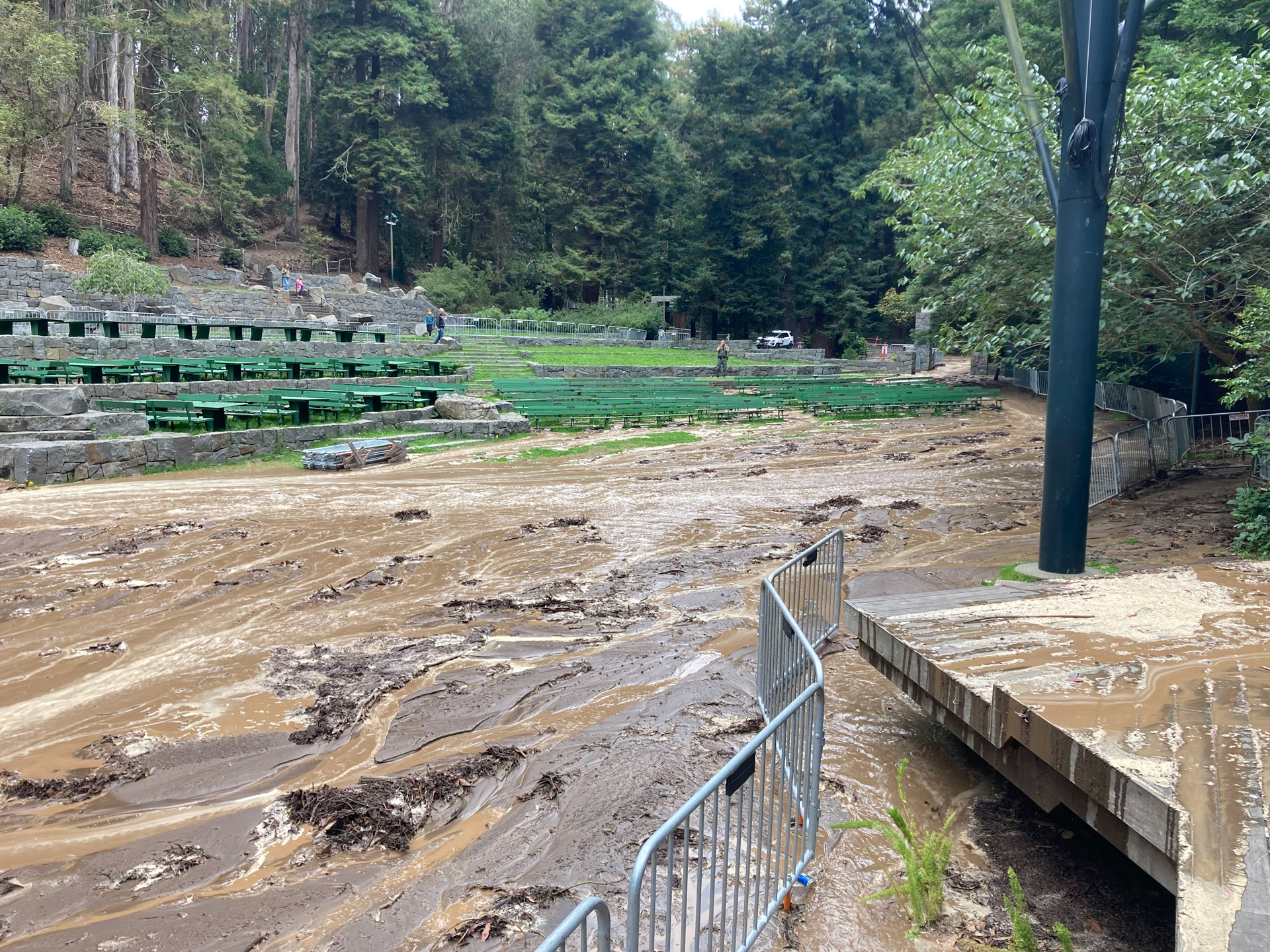 Thick mud covers the ground up to green benches in the park.
