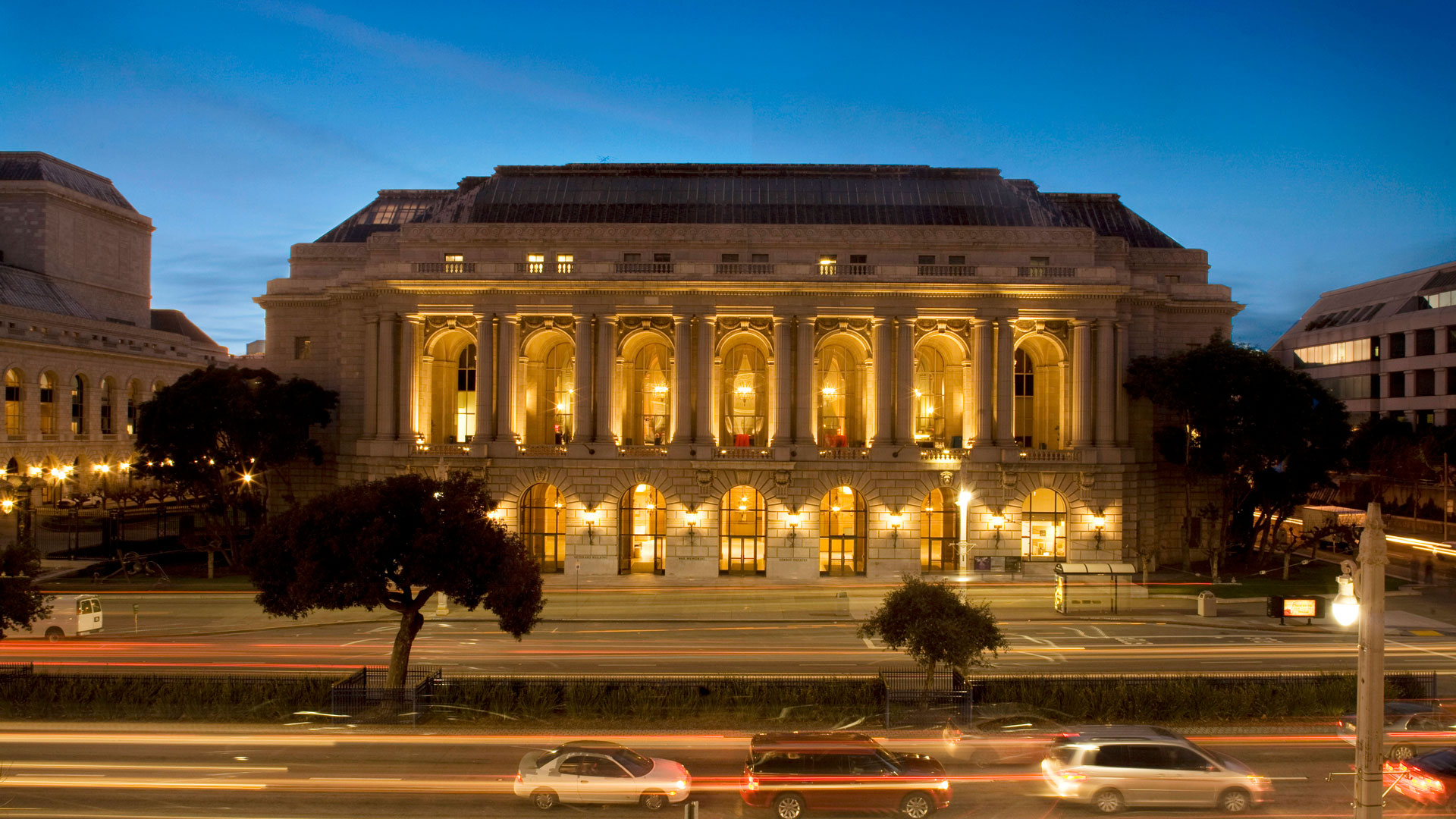 Lit-up exterior of beaux arts building at night.