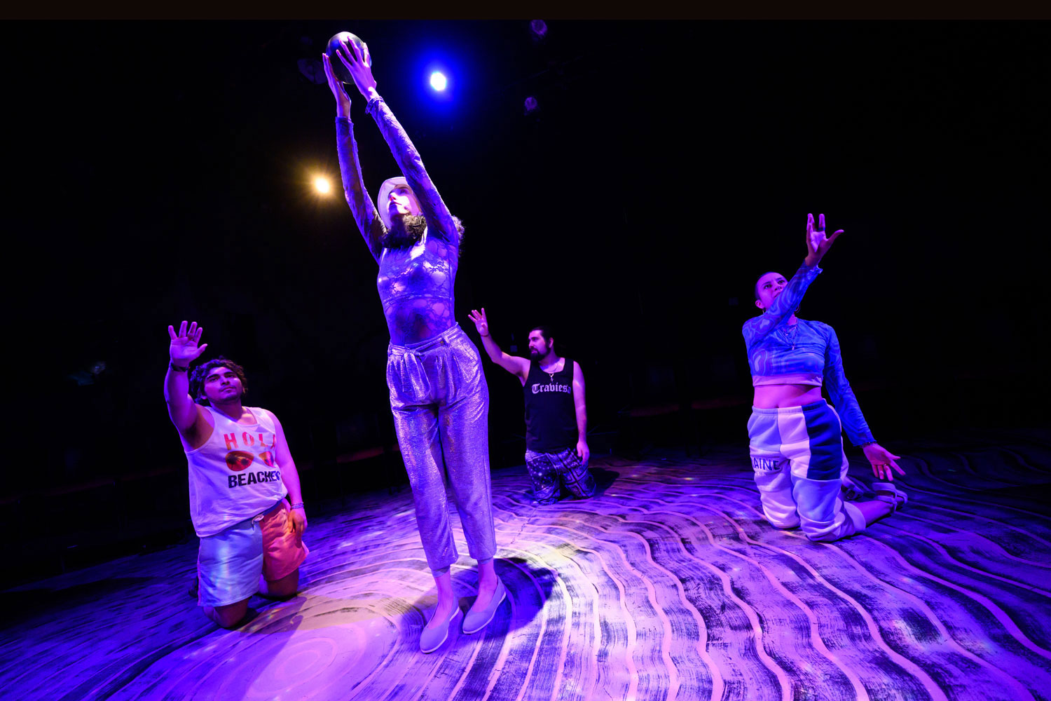 people perform on a stage bathed in purple light