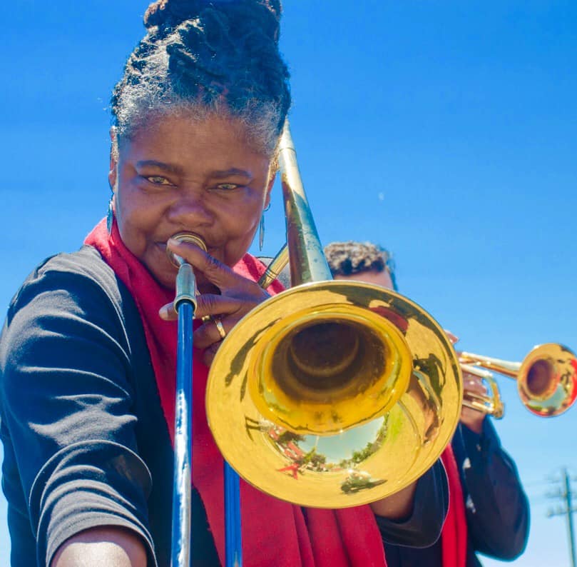 Dr. Angela Wellman looks directly into the camera as she plays her trombone.