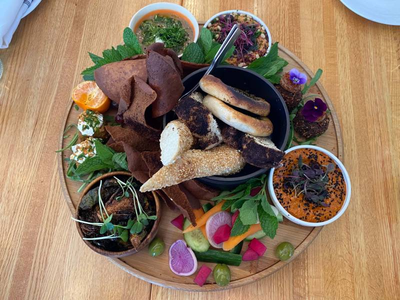 An abundant spread of Palestinian mezzes served on a circular wooden board.