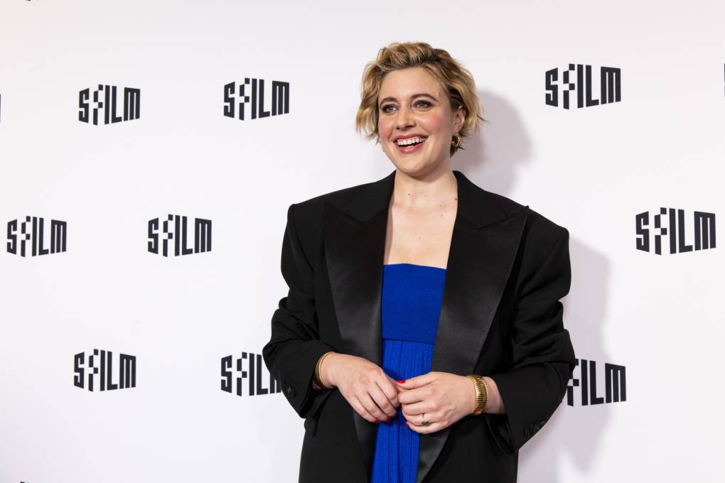 A person in a blue dress in front of a backdrop with the words "SFFILM" written on it.