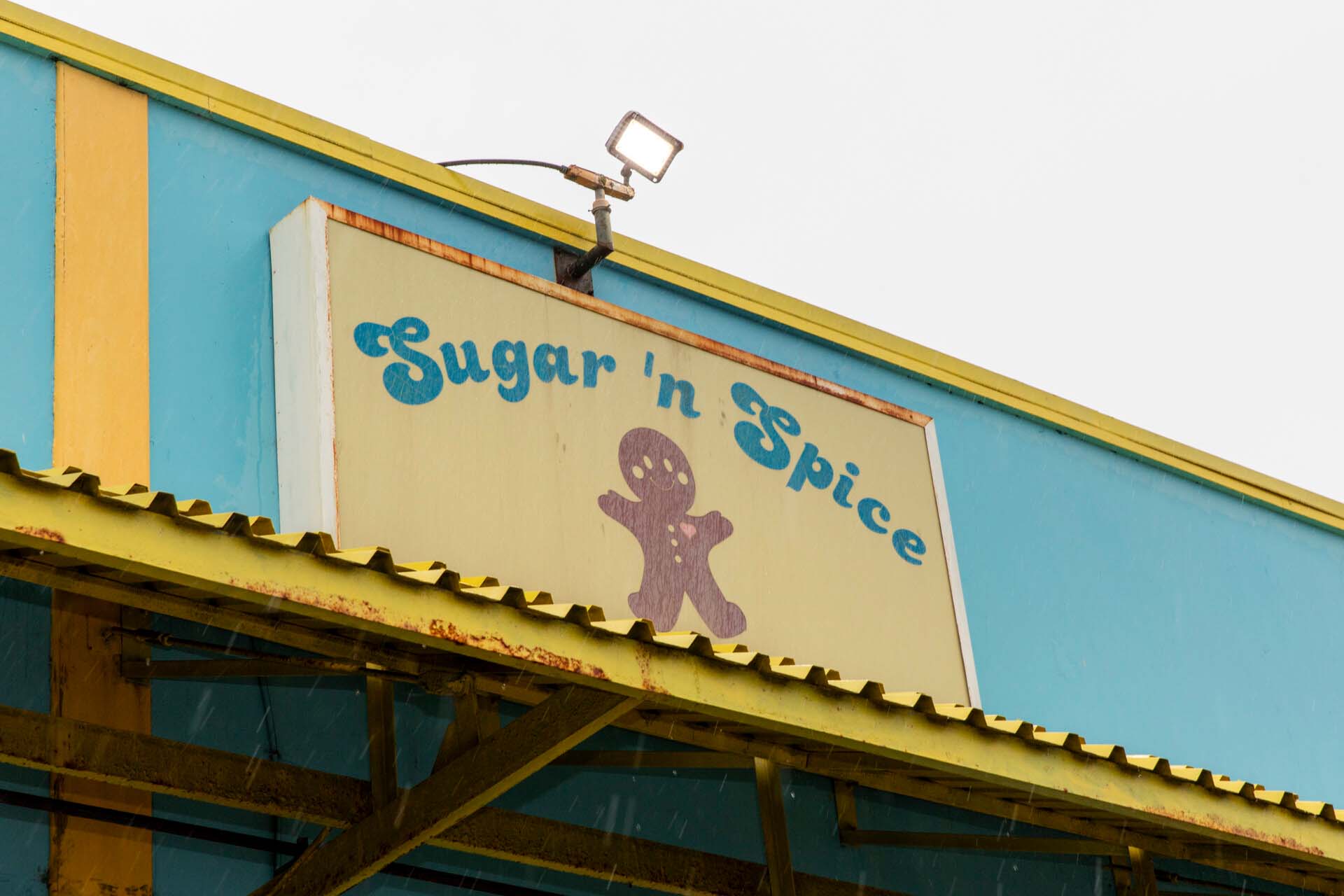 The sign outside a baking supply shop reads "Sugar 'n Spice" with a picture of a gingerbread man underneath.