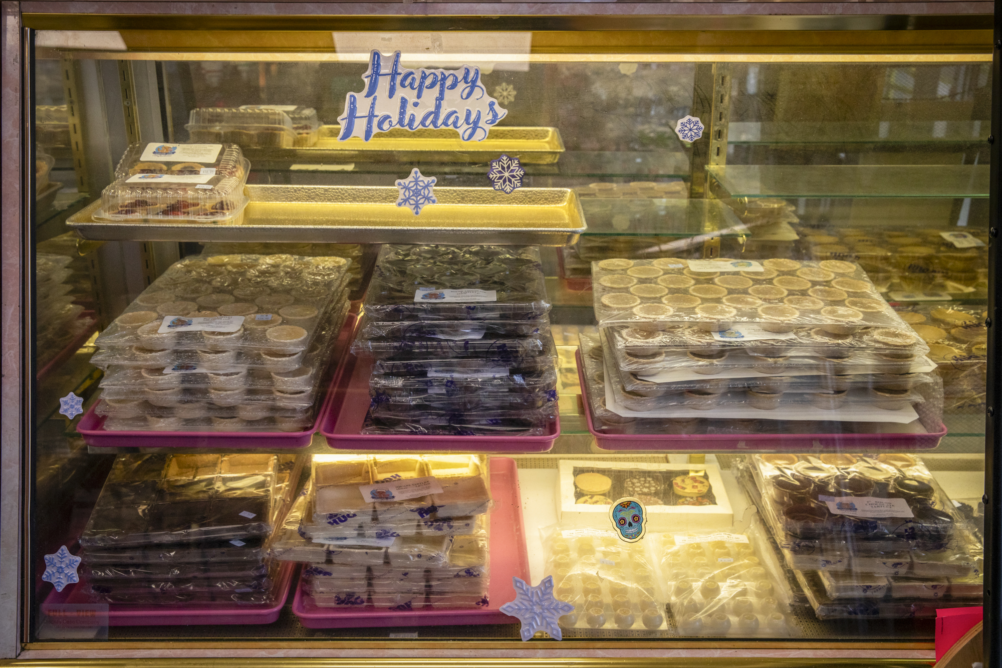 Display case in a cookie decorating and baking supply shop. A sticker on the glass reads, "Happy Holidays."