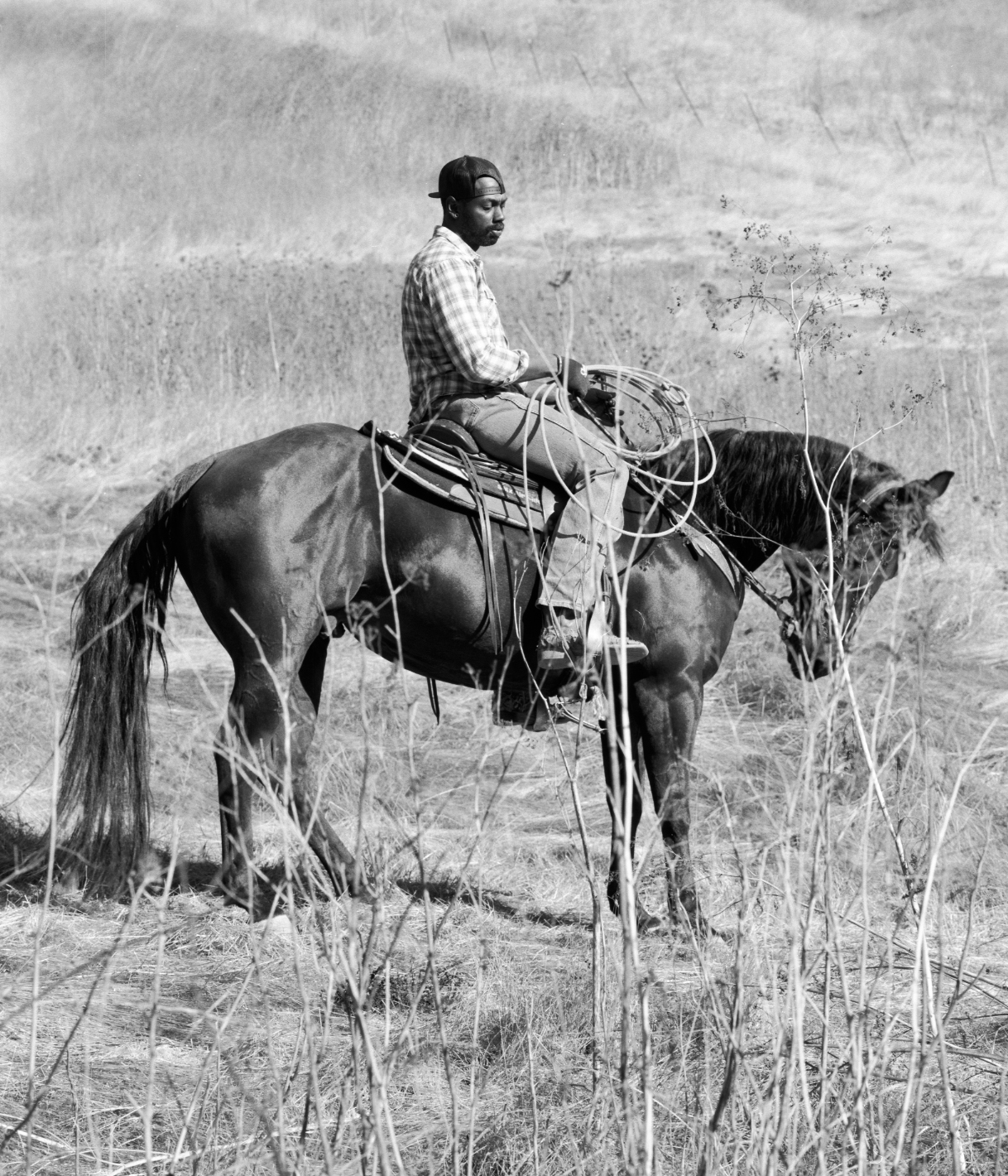 Black-and-white photograph of a Black man on horseback, in profile
