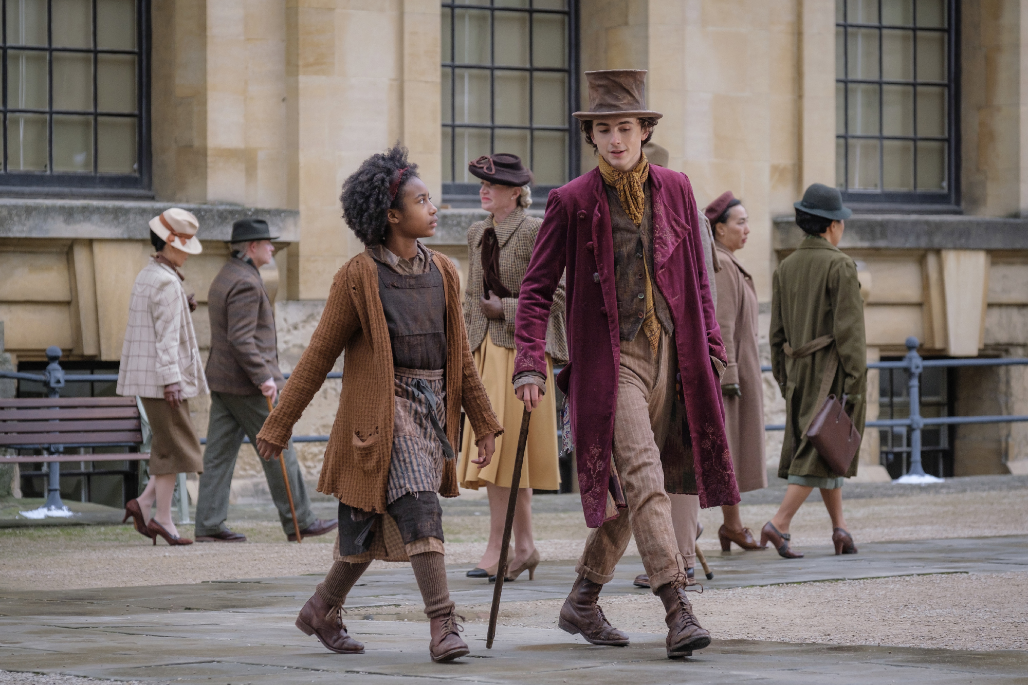 Young girl and man walk across street in muted Victorian clothes 