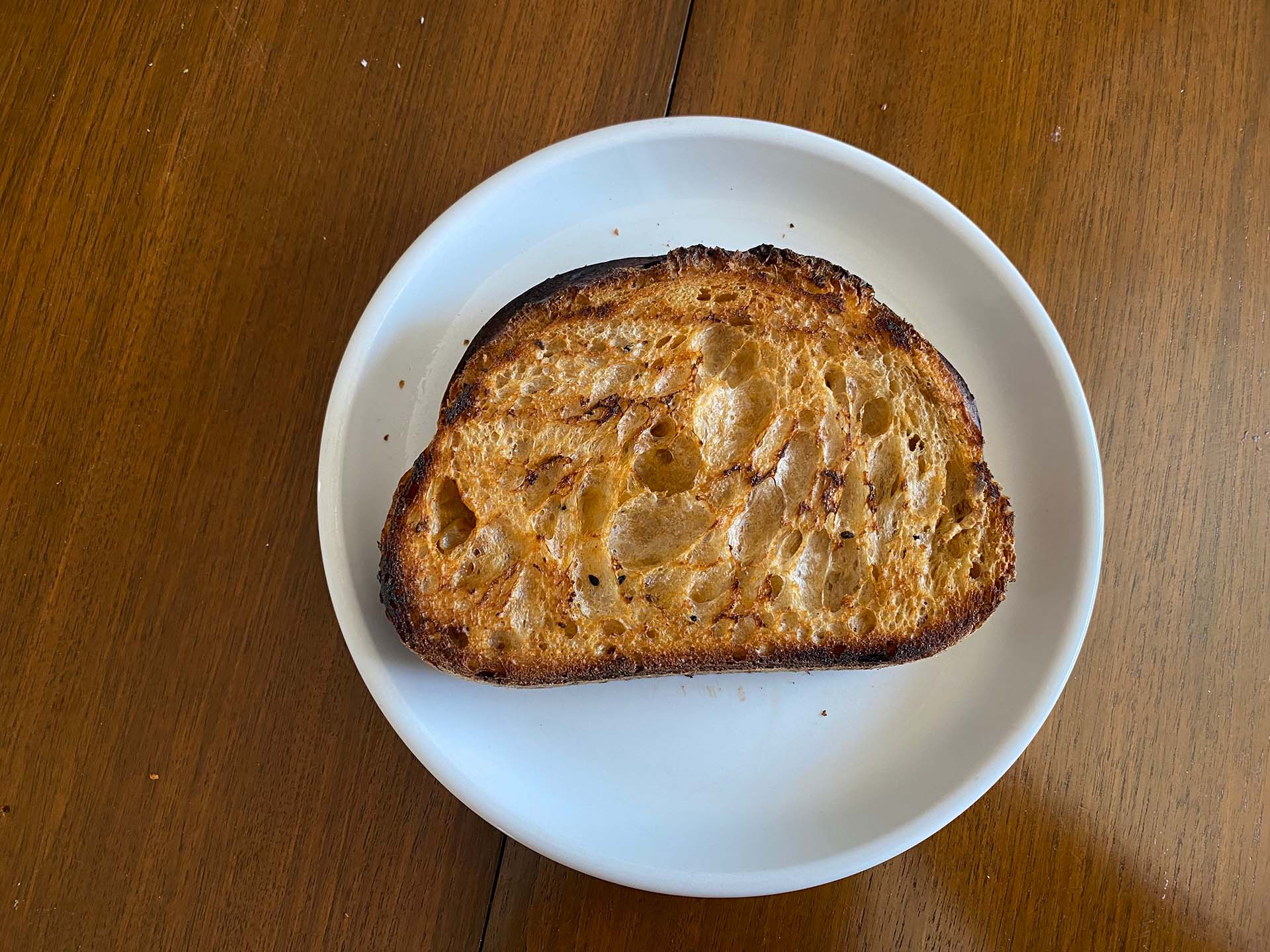 A slice of toasted sourdough bread on a white plate.