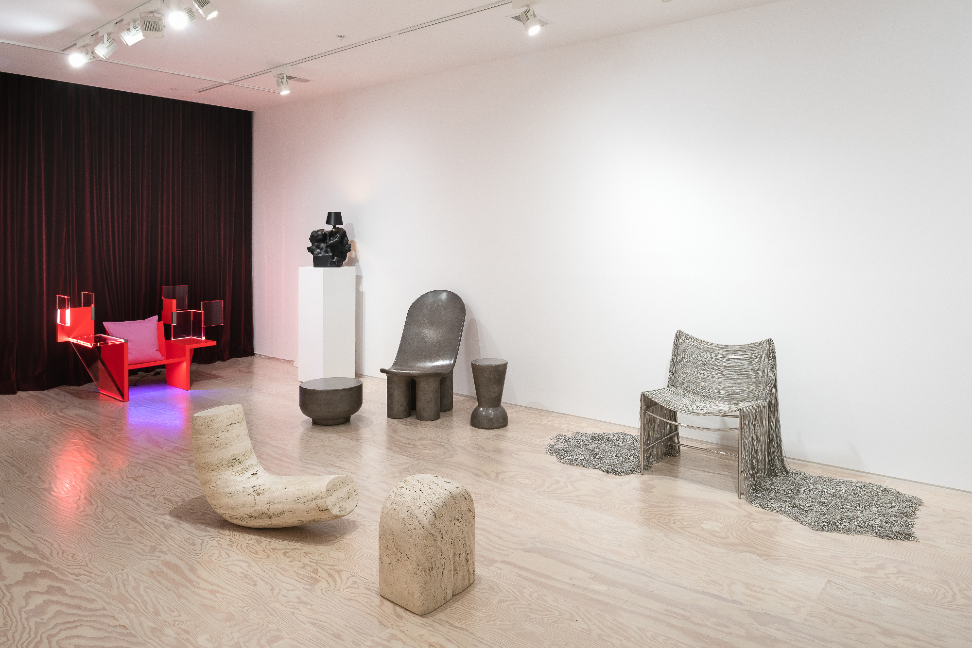 Various chairs, stools and lamps in light-wood floor, white-walled gallery