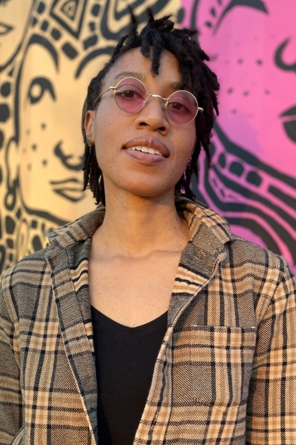 Person in plaid blazer with rose-tinted glasses