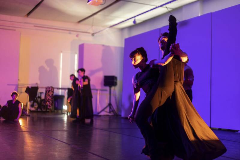 Ballet dancers rehearsing against a purple backdrop.