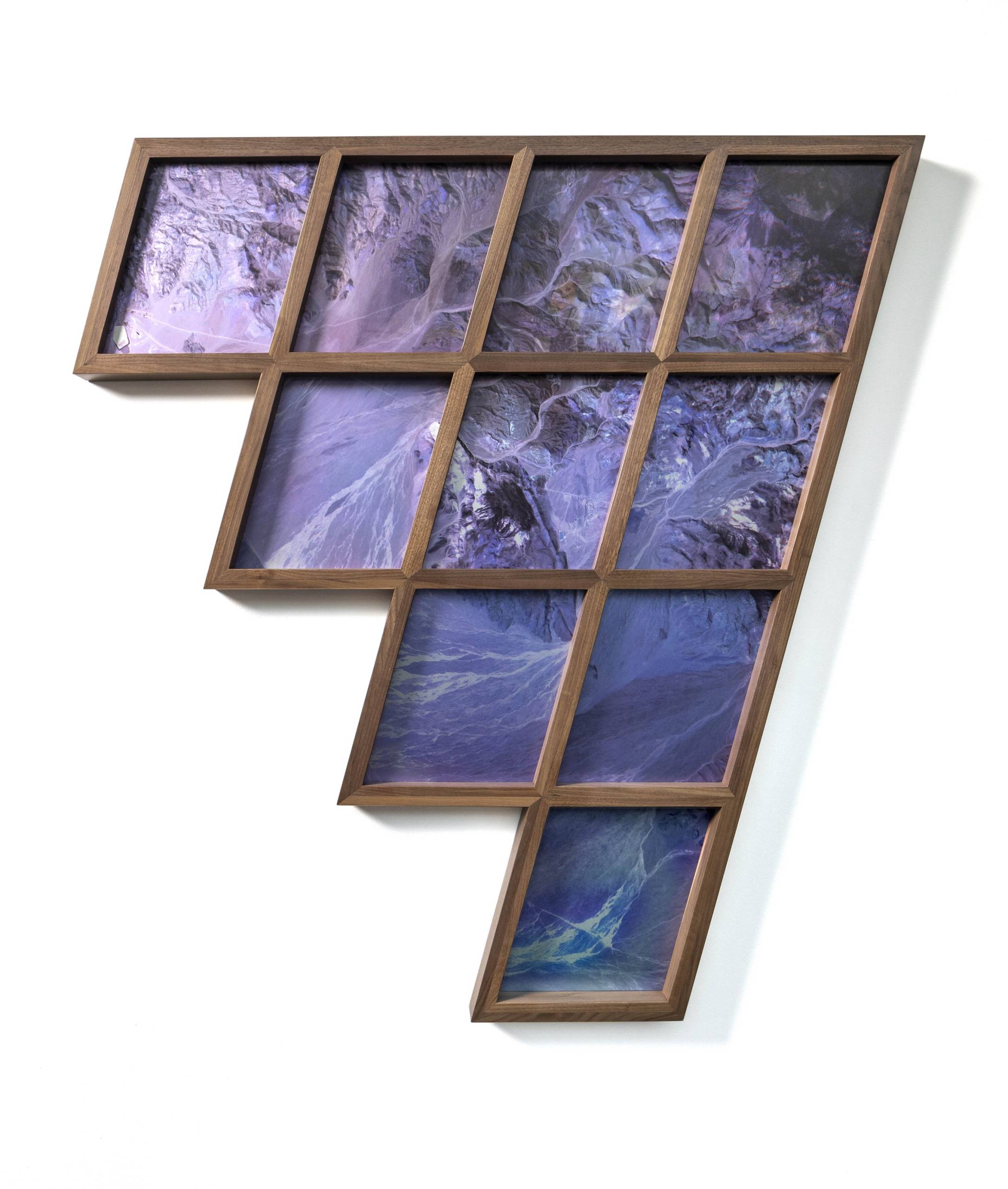 Framed photographic piece with rhombus-shaped prints laid out in stair step-like grid, showing purple aerial landscapes