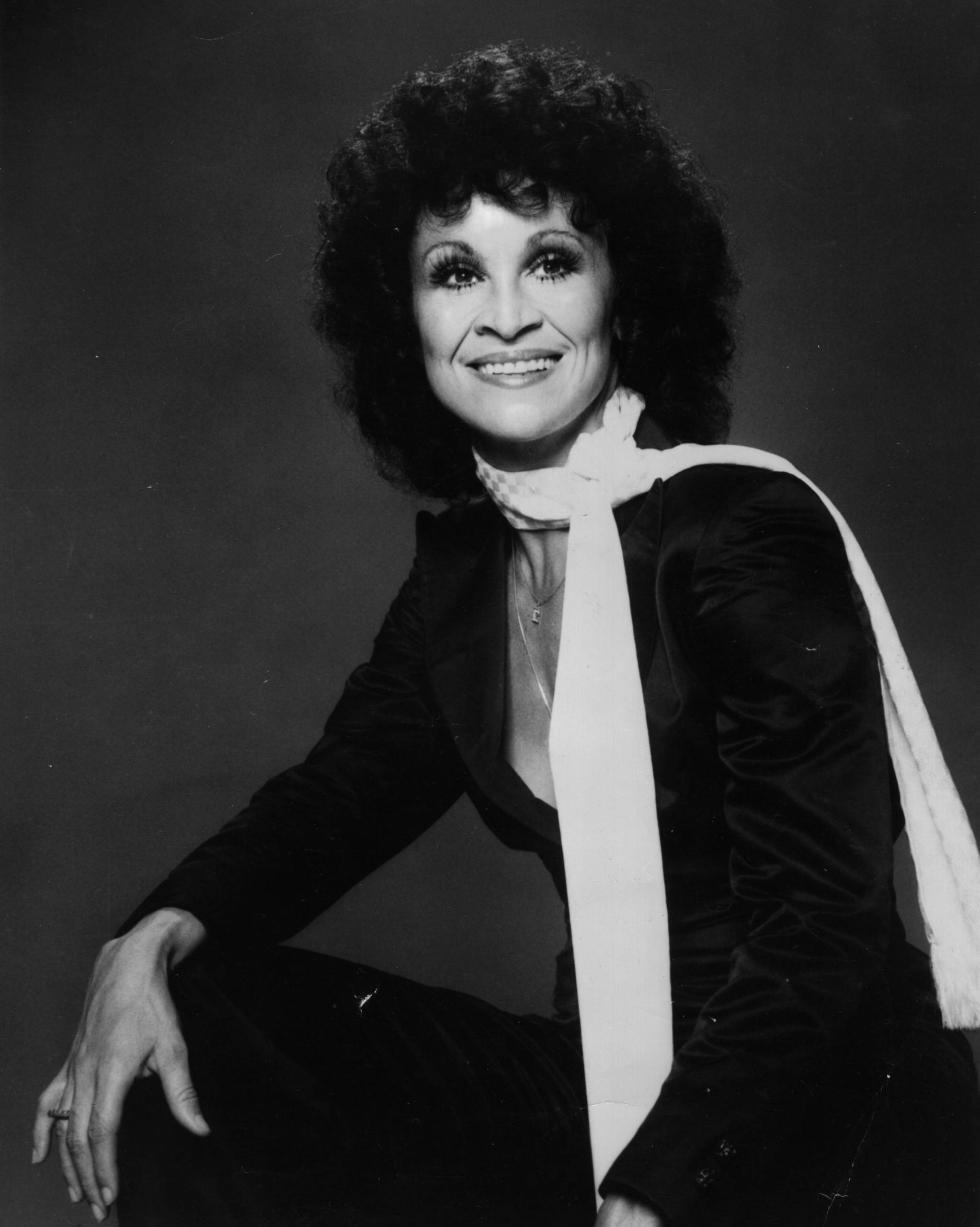 A smiling woman sits for a photographic portrait.