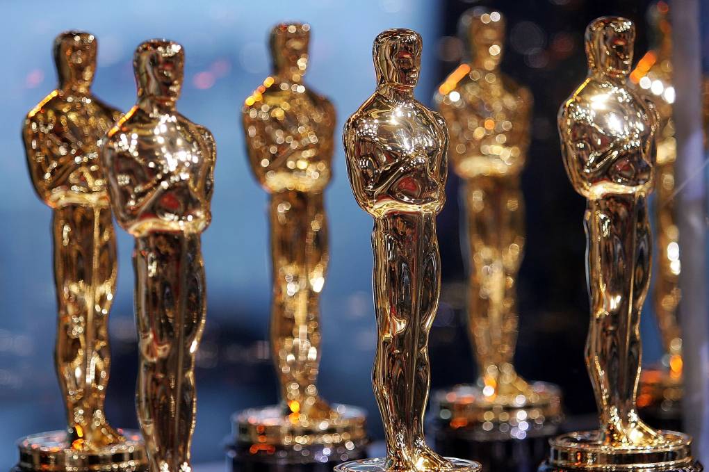 A collection of 7 Oscars standing together on a podium.