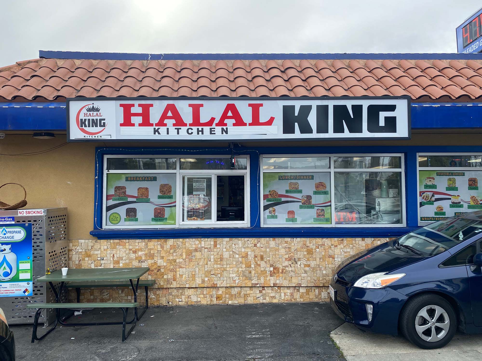 The facade of a gas station convenience store, with a big sign for "Halal King Kitchen."