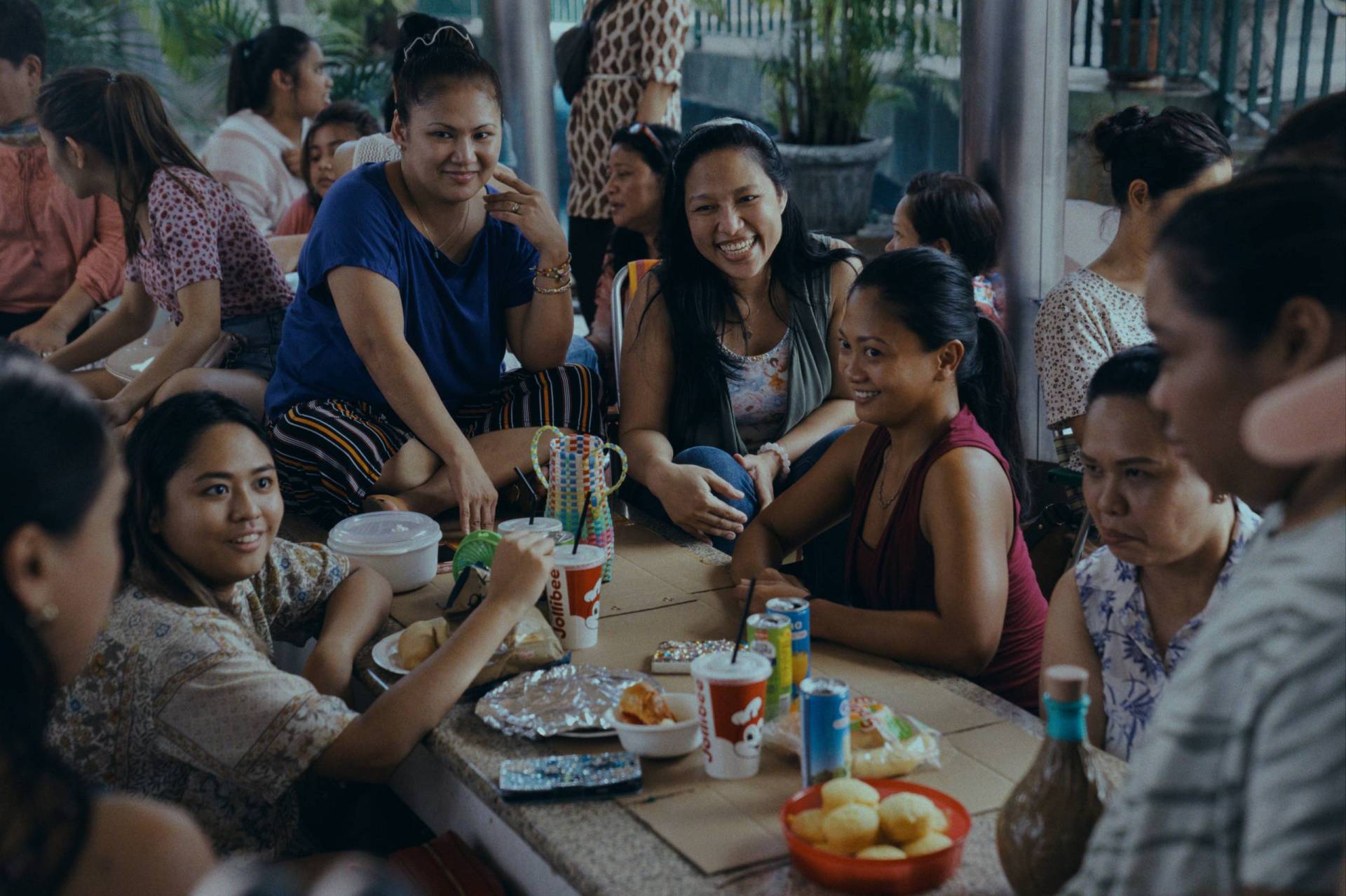 A family gathers around a table, seated casually, and chats.