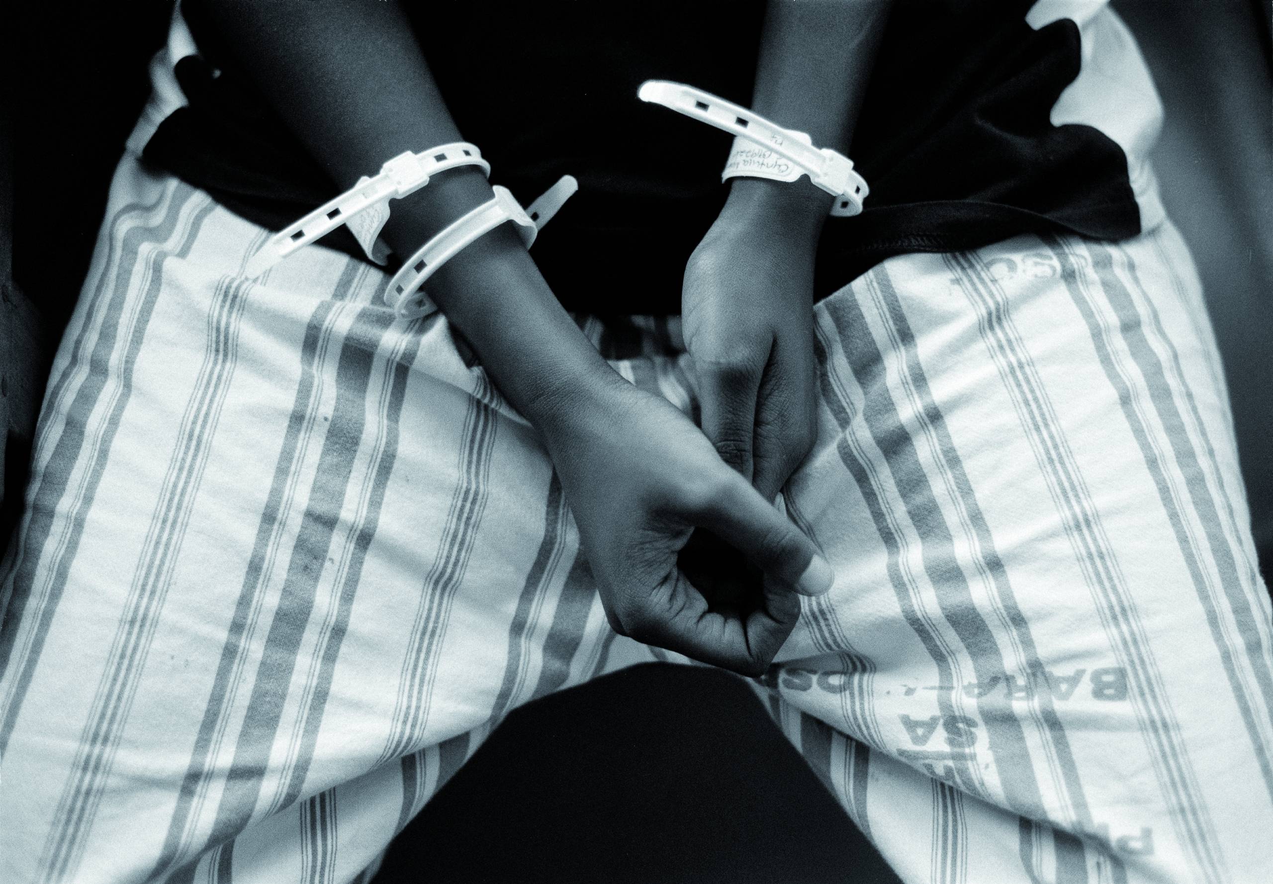 A black-and-white photo of hands with hospital bracelets over plaied