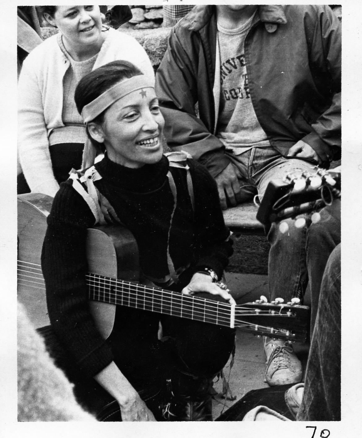 A candid shot of Betty Reid Soskin in the 1960's holding a guitar while sitting in a music circle in the Asilomar area of Monterey Bay.