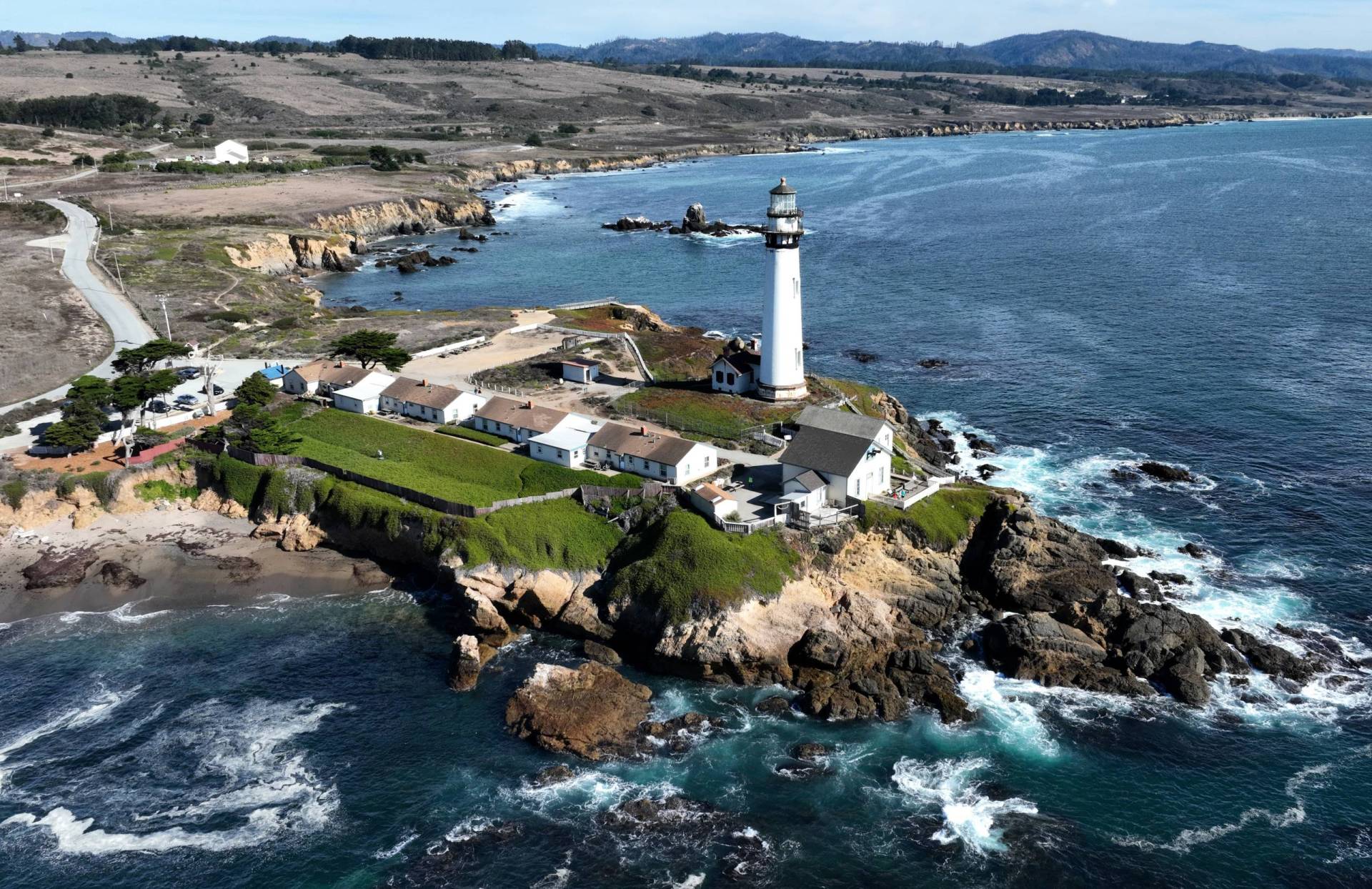 A drone view of a lighthouse on a rugged coastline.