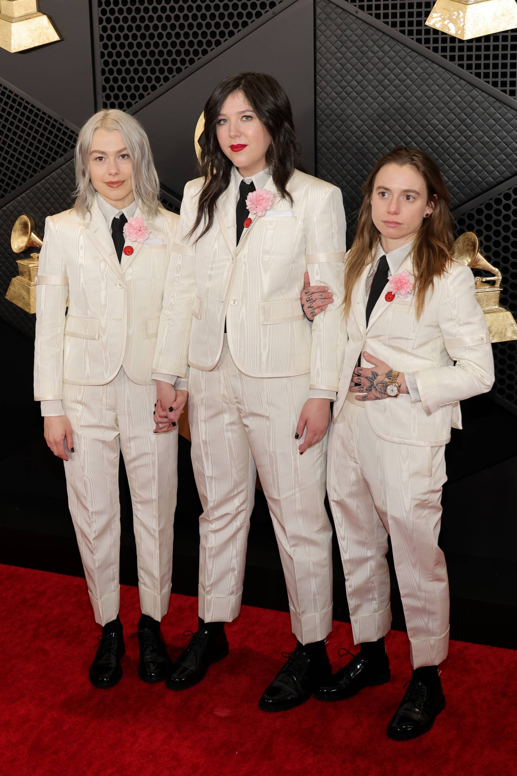 Three young women in matching white suits and red ties.