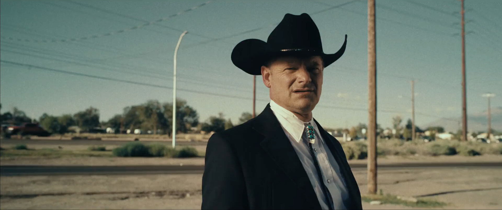 Person in cowboy hat and suit in arid landscape