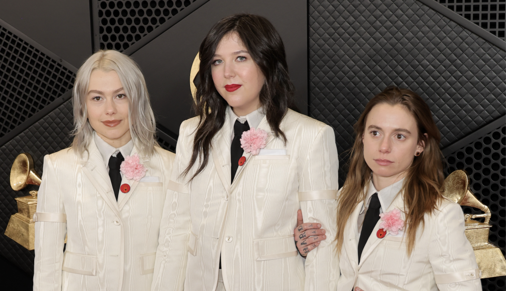 Three young women in matching white suits and red ties.