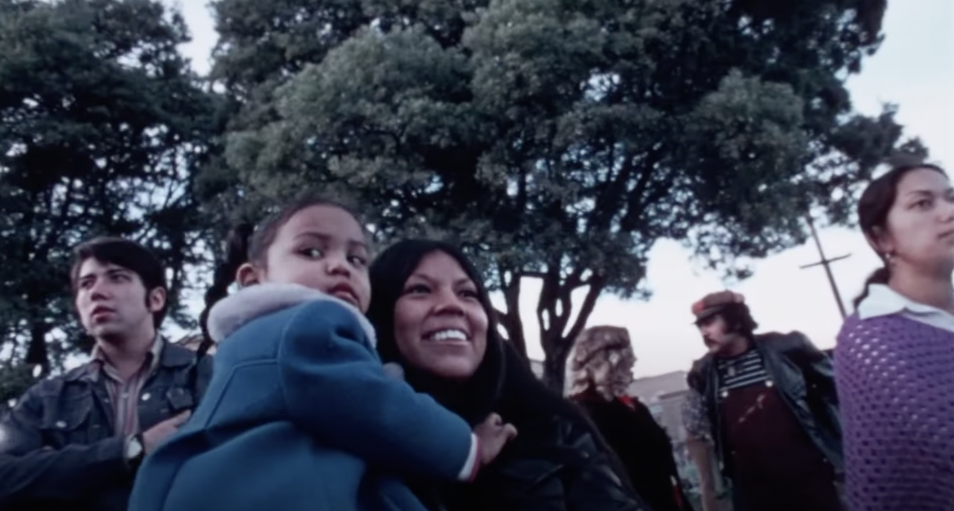 a Latina woman holds a child in a San Francisco park, circa 1970s