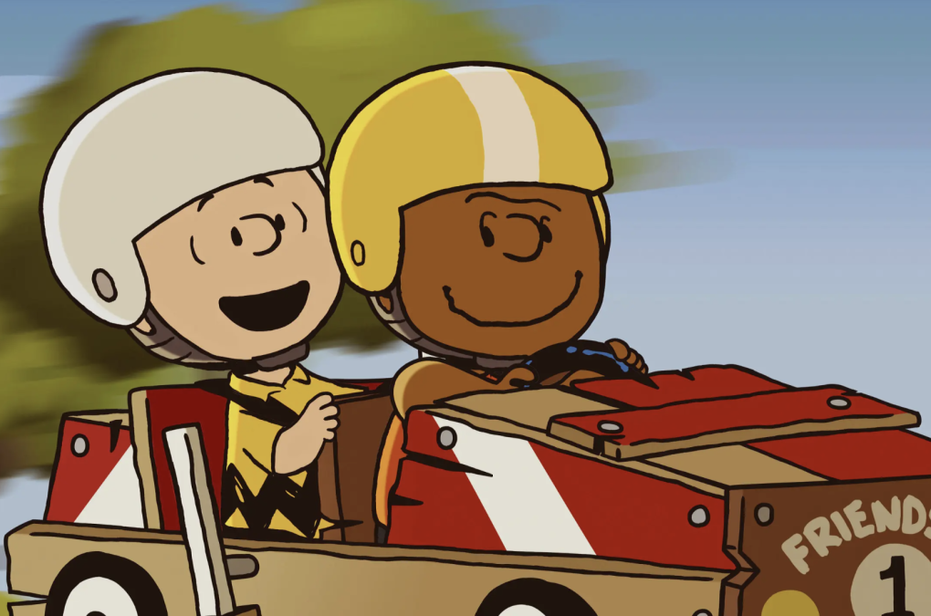 An illustration of two boys, both wearing helmets, riding in a soapbox.