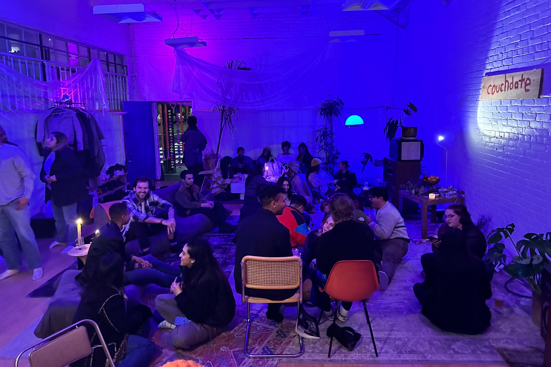 A blue-lit room filled with multiple people sitting and talking.