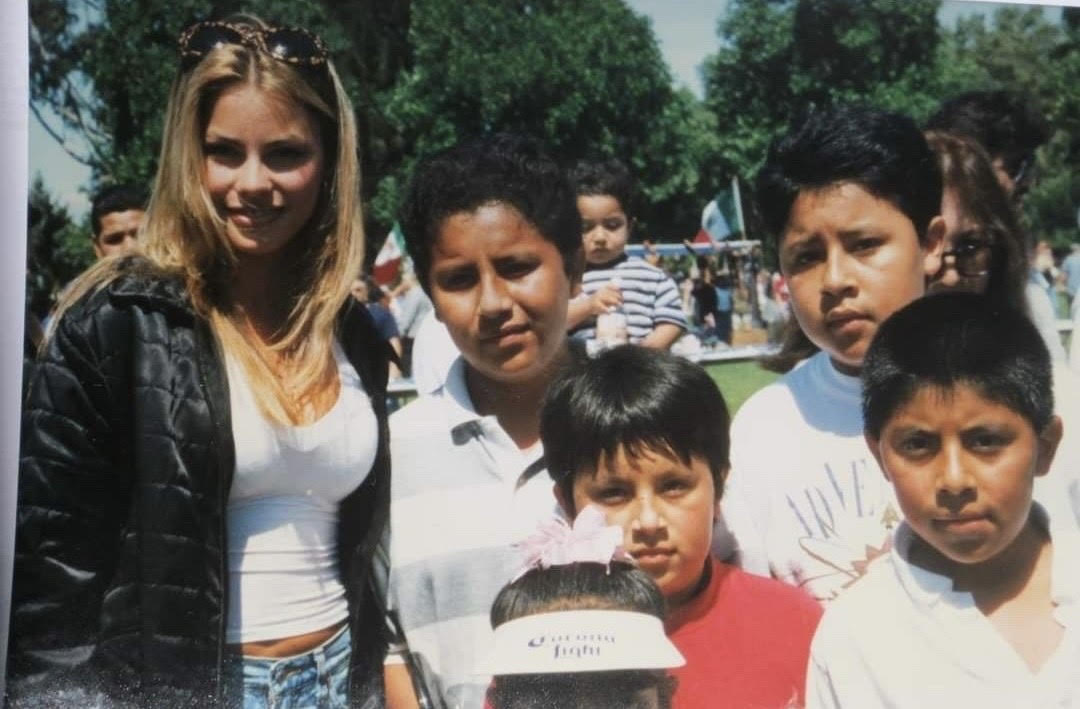 a group of Latino kids stand next to the actress Sofia Vergara at an outdoor park