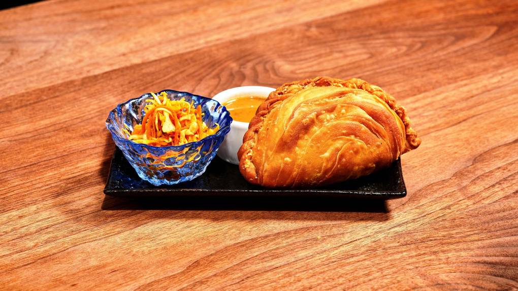 Curry puff on a plate with curry dipping sauce.