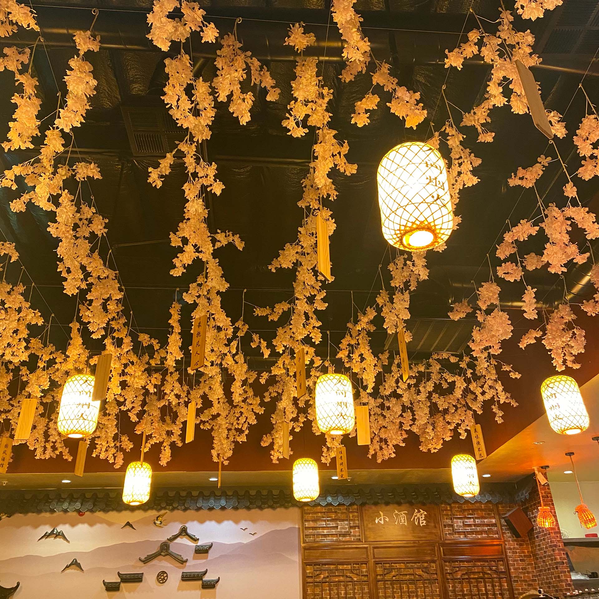 Spring blossoms and paper lanterns hanging from the ceiling of a traditionally decorated Chinese restaurant.