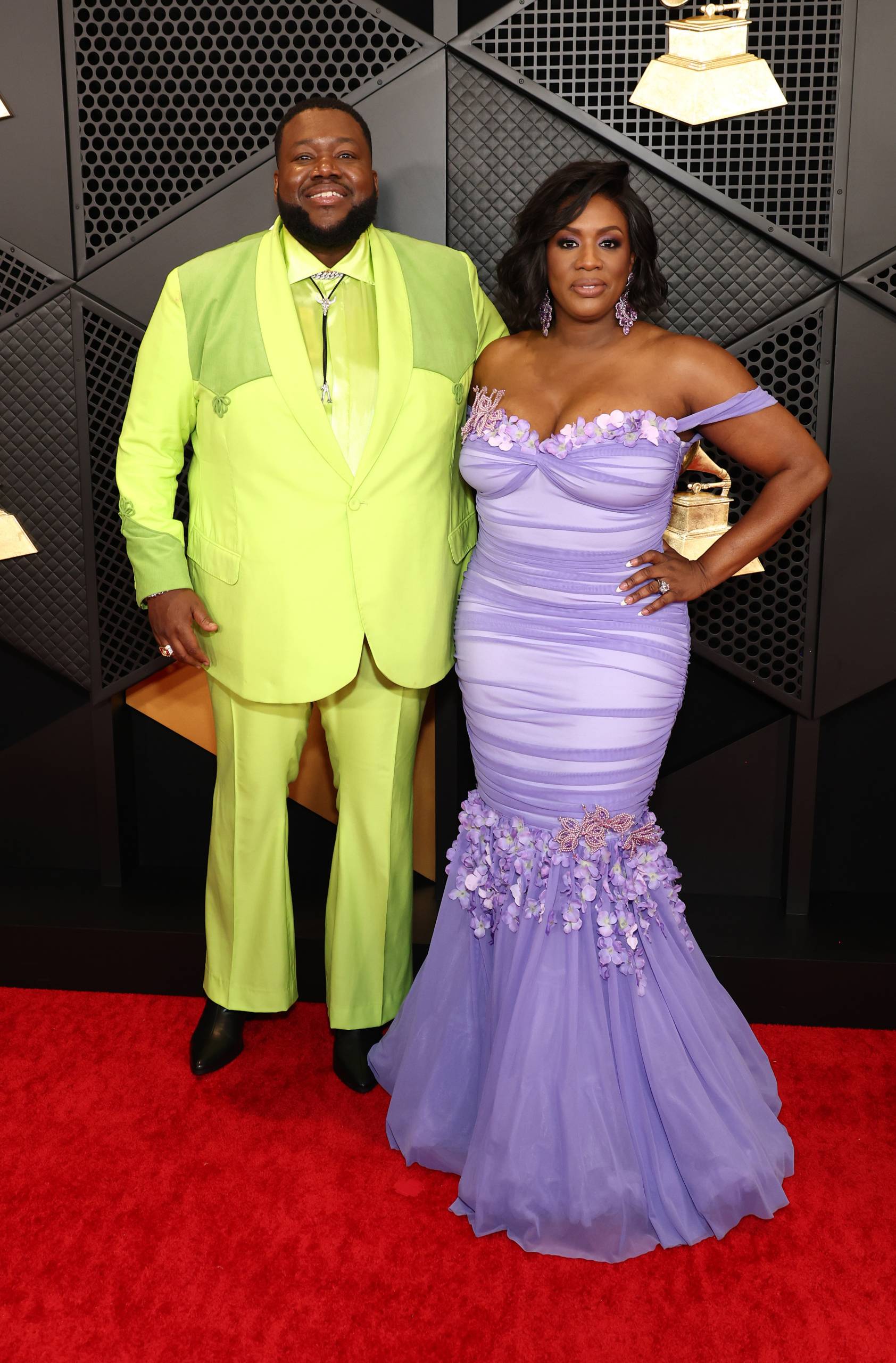 A man in a neon yellow suit and a woman in a lilac fitted gown.