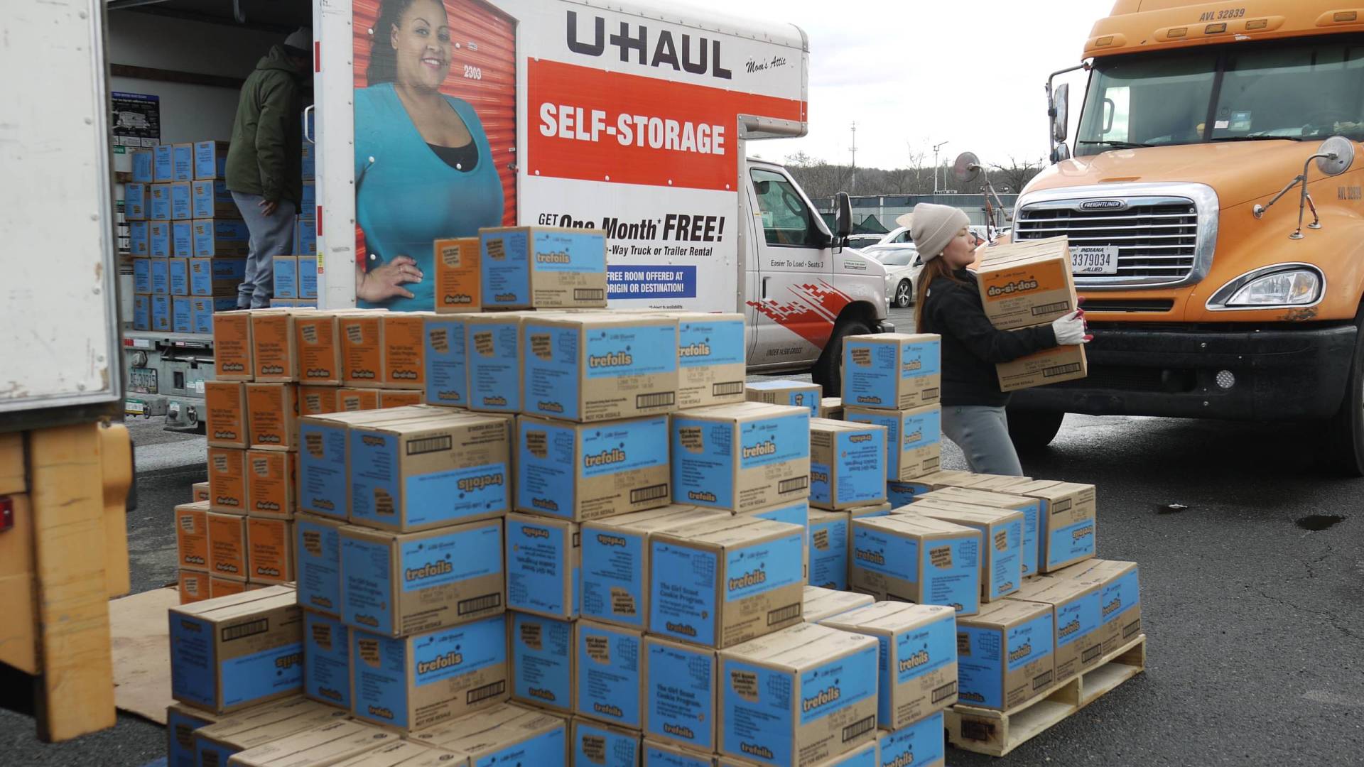 Piles of blue and brown boxes sit next to a U-Haul truck.