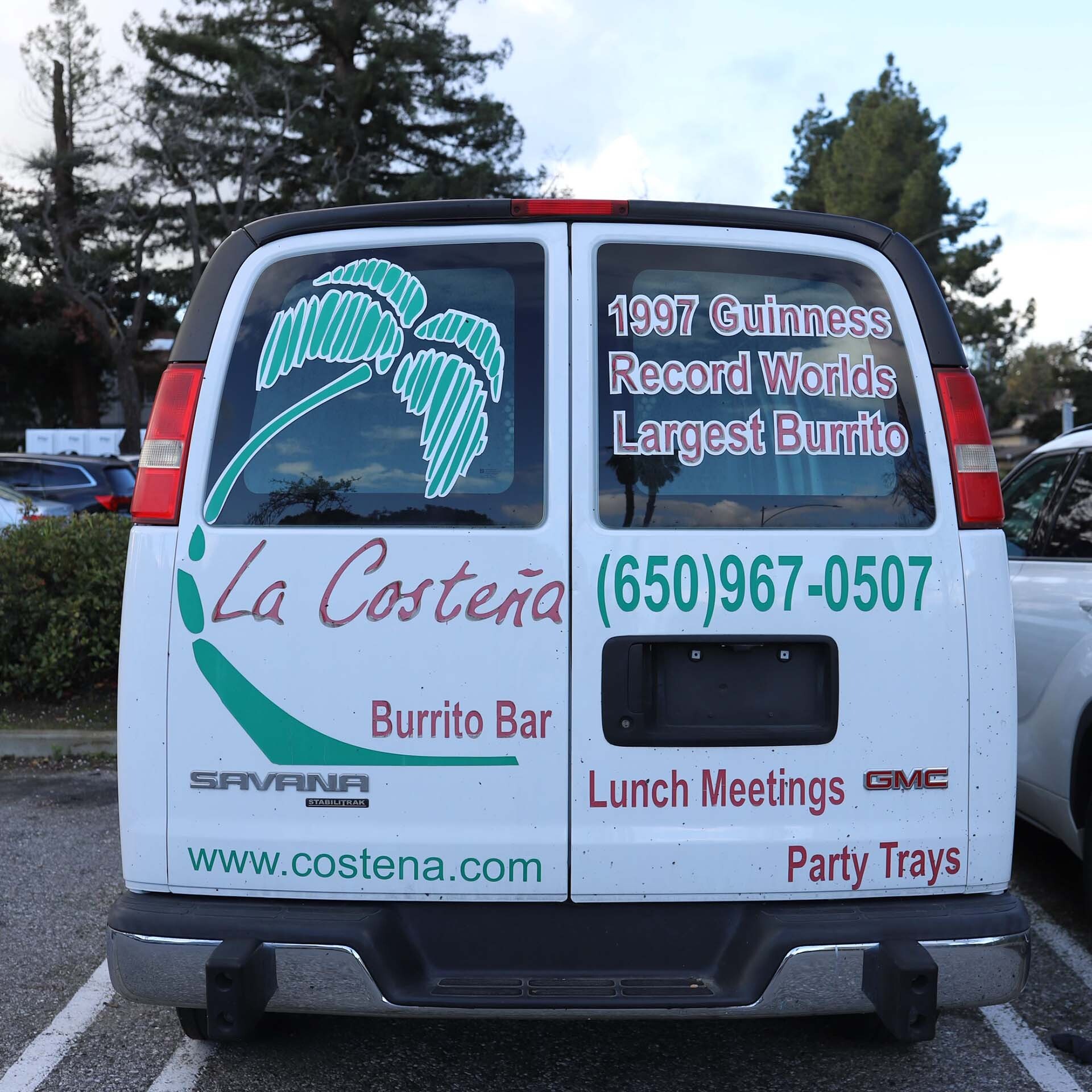 a van parked in a parking lot that displays a restaurant's claim to burrito fame in 1997