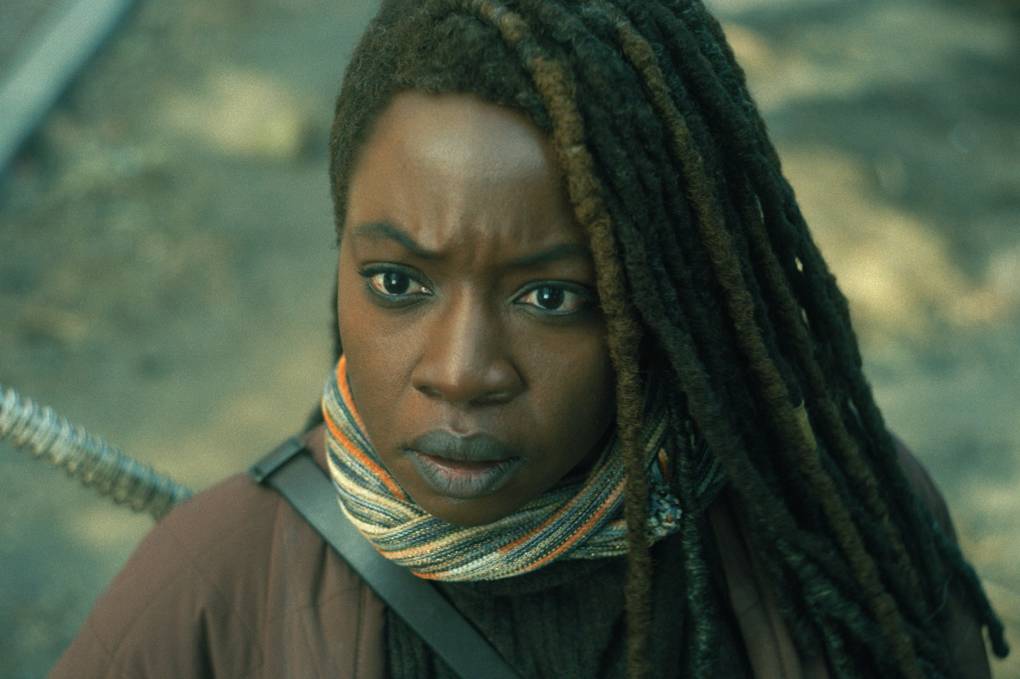 Close up of a Black woman with long dreadlocks looks ahead, frowning.