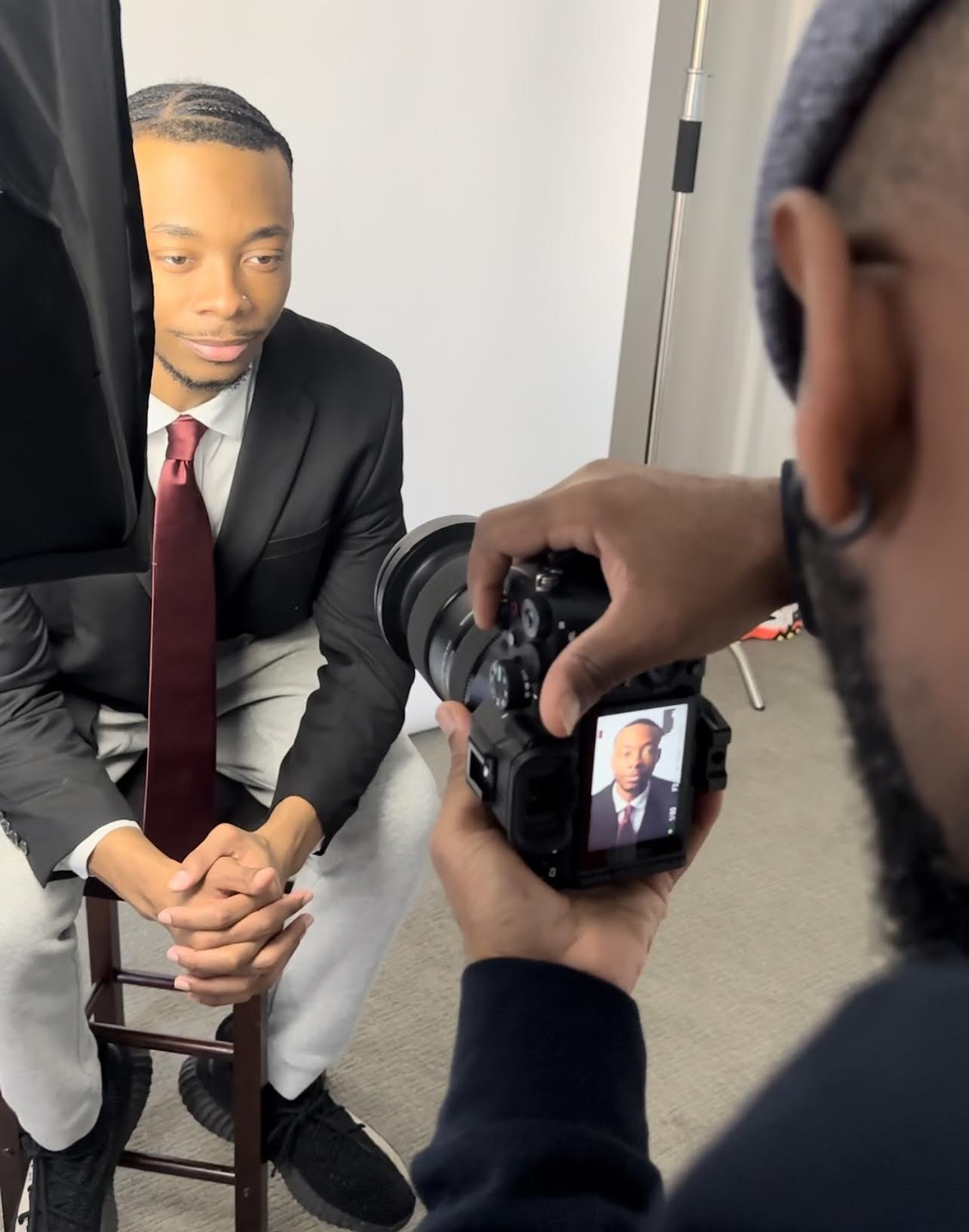 Dwayne Davis wears a red tie and an a dark blazer as he poses for a photoshoot with Jamal Josef.