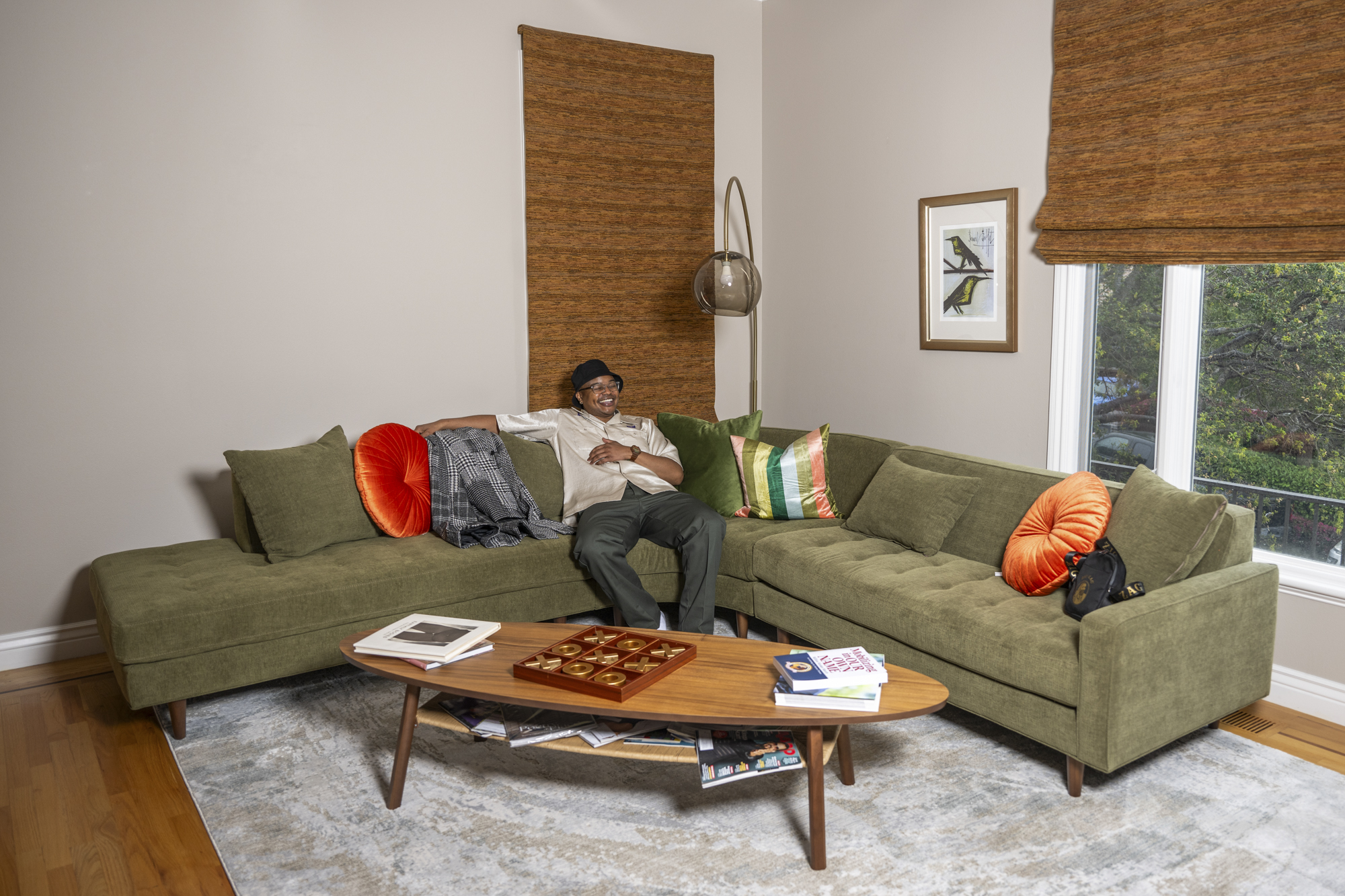 Person sits relaxed in corner of long green couch in living room