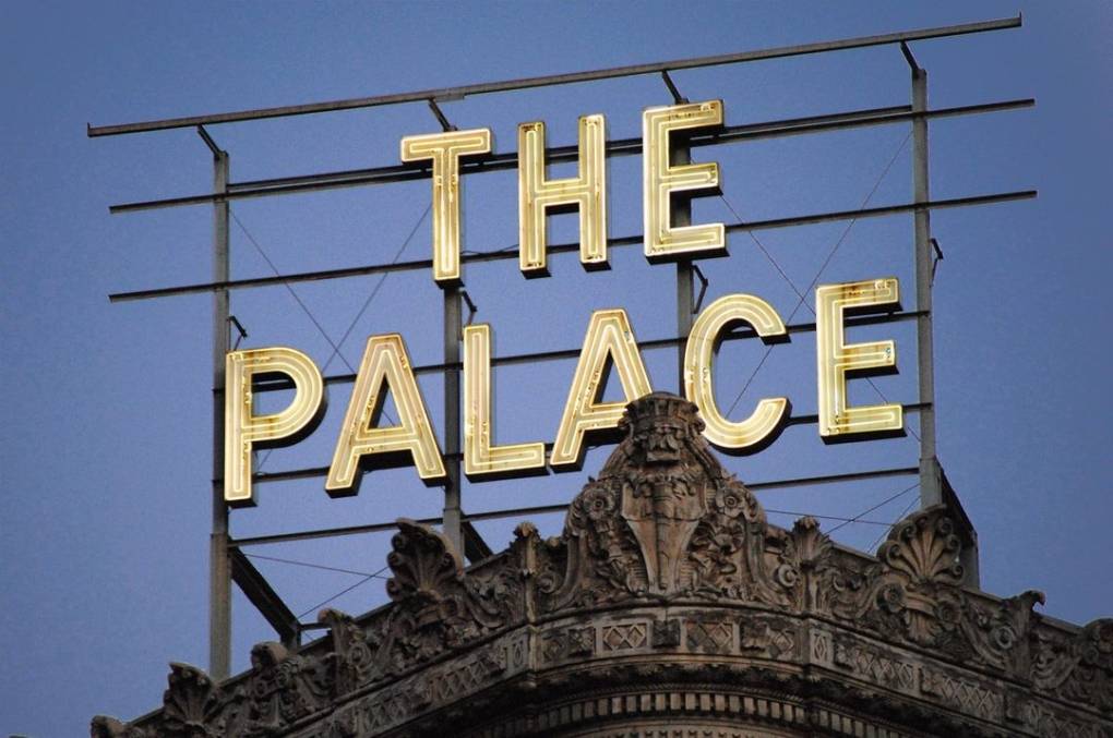 White illuminated letters of 'THE PALACE' on a rooftop