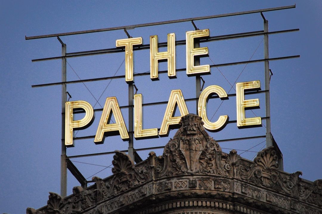 White illuminated letters of 'THE PALACE' on a rooftop