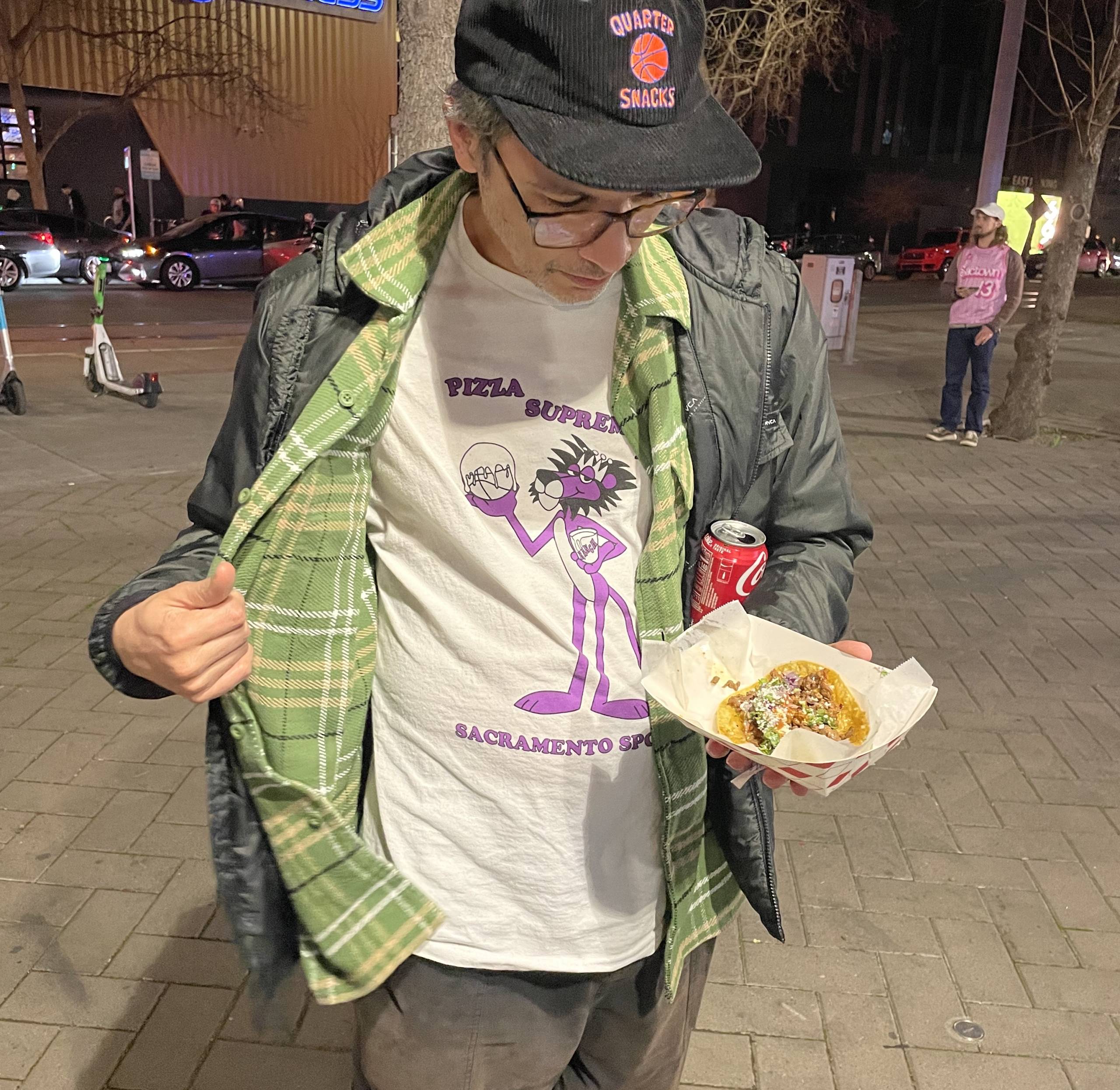 a basketball fan eats a taco in front of a basketball arena