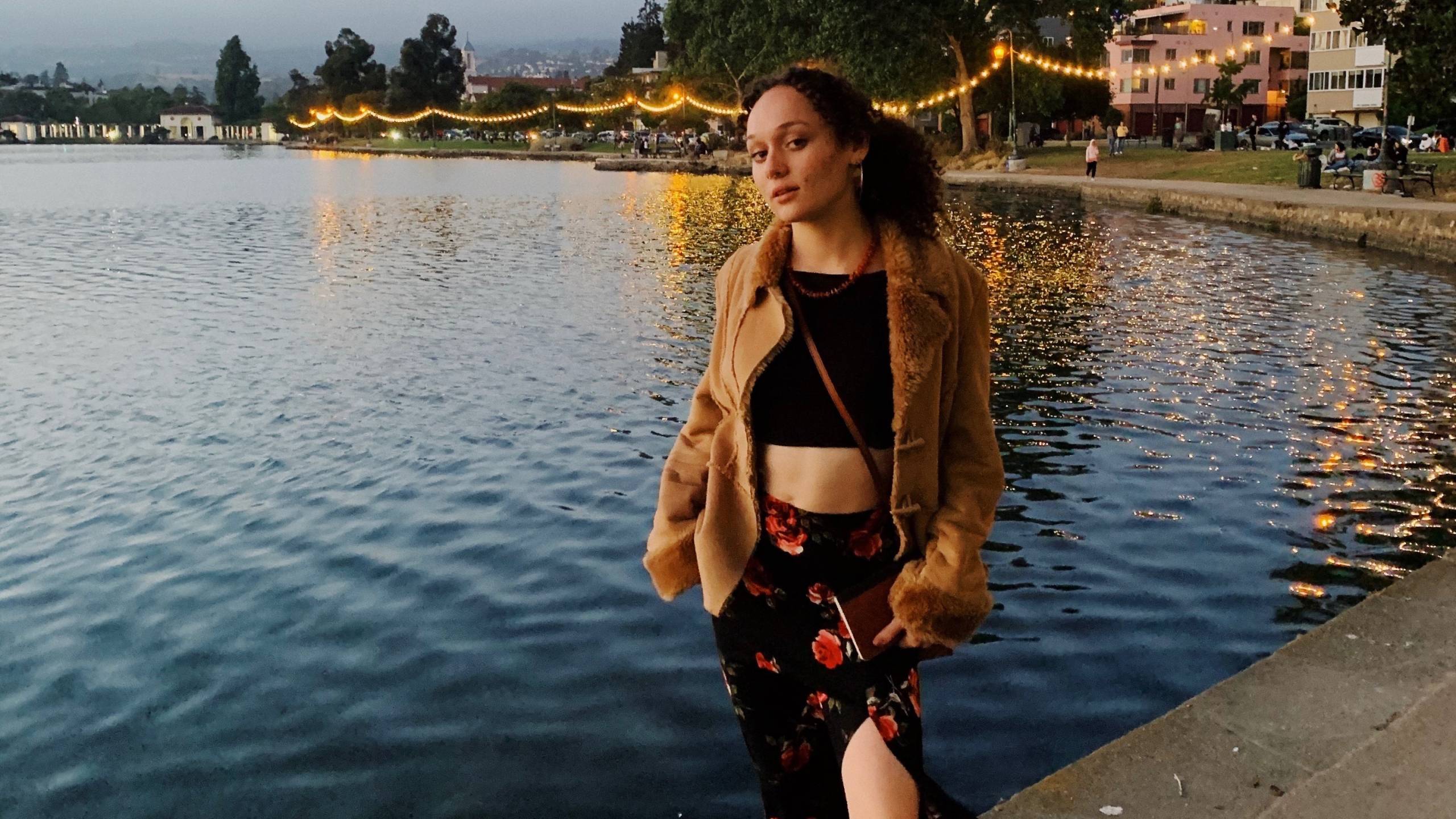 A young woman poses in front of Lake Merritt.