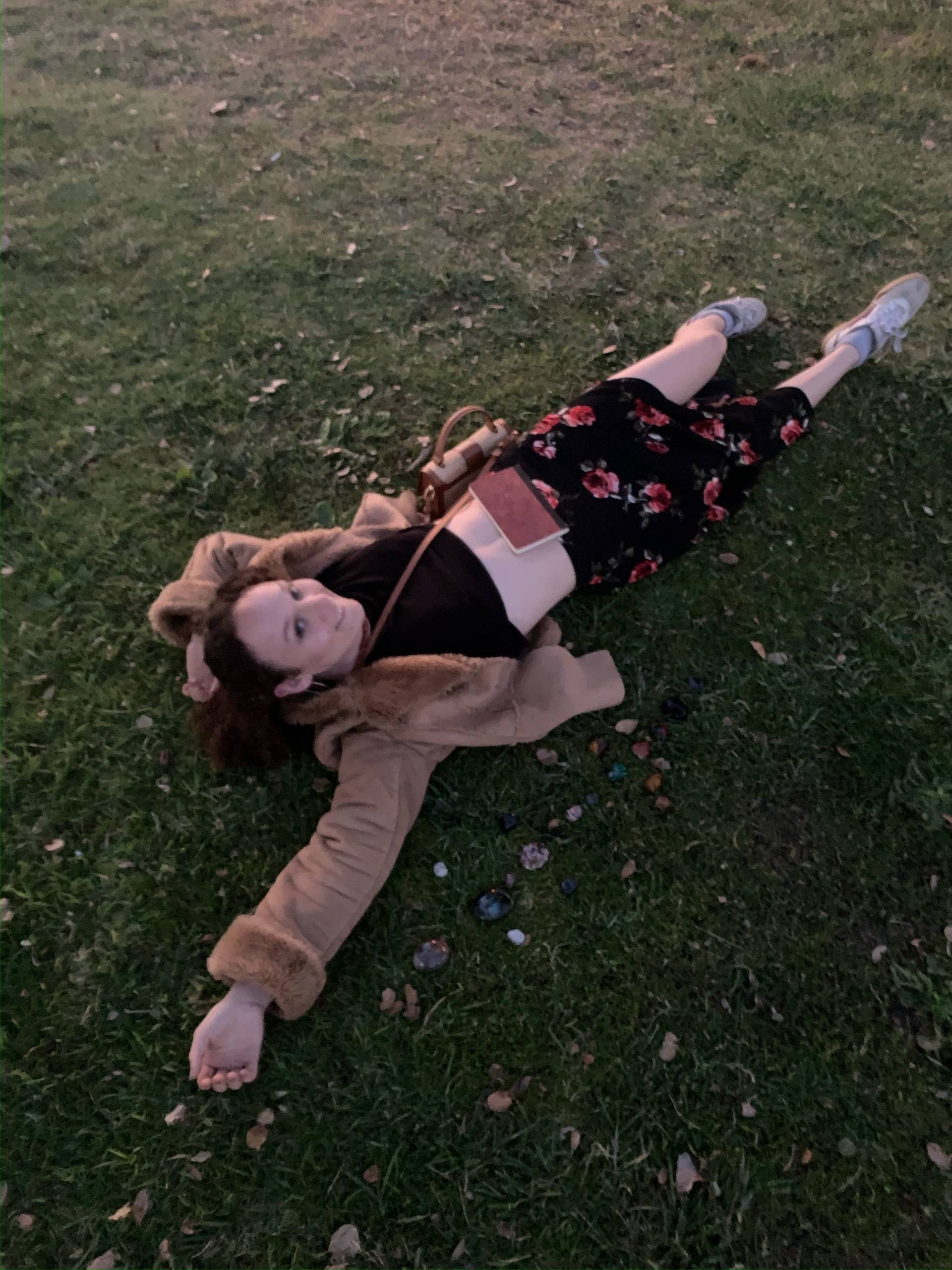 A young woman lays in the grass at Lake Merritt.