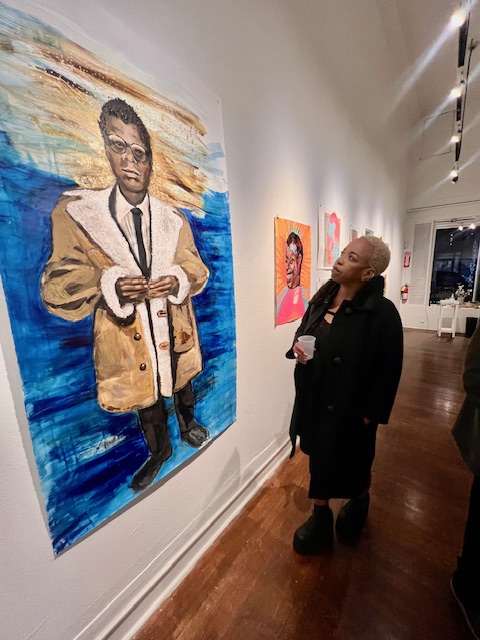 Filmmaker Celia Peters stands in admiration of an image of James Baldwin on the wall at the Joyce Gordon Gallery.