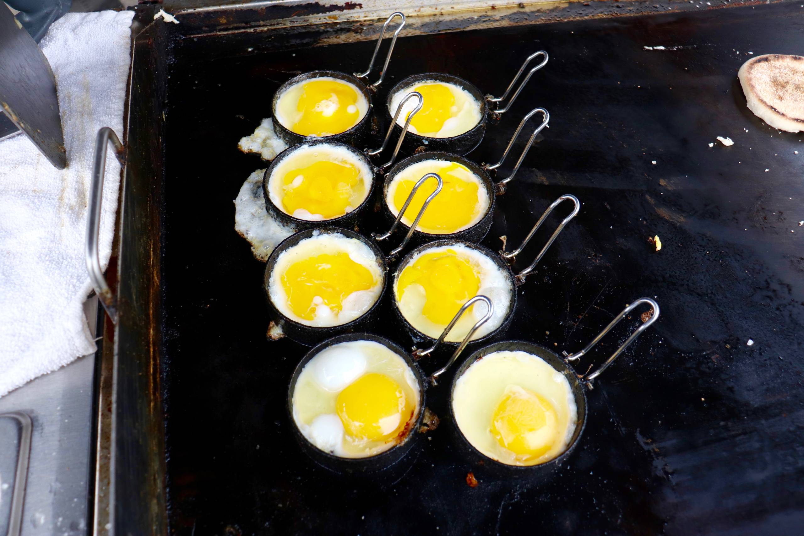 an order of eight eggs are prepared on a portable outdoor griddle